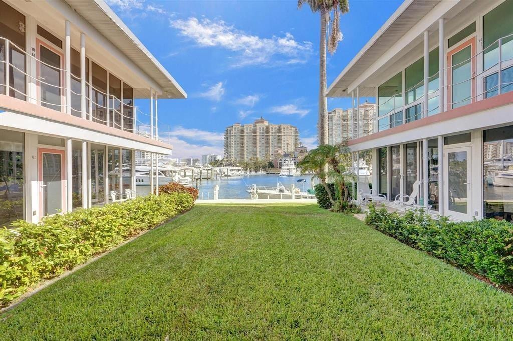 2760 YACHT CLUB Boulevard, #10C, Fort Lauderdale, Fort Lauderdale, FL 33304 Expansive manicured lawn framed by modern residential architecture on both sides, featuring lush tropical landscaping, mature palm trees, and a sparkling resort-style pool with waterfront views beyond
