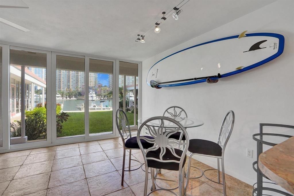 2760 YACHT CLUB Boulevard, #10C, Fort Lauderdale, Fort Lauderdale, FL 33304 Modern dining area with expansive glass sliding doors opening to manicured grounds, neutral tile flooring, track lighting, and contemporary metal-frame seating