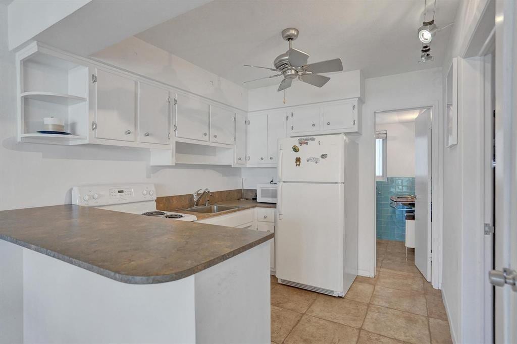 2760 YACHT CLUB Boulevard, #10C, Fort Lauderdale, Fort Lauderdale, FL 33304 Bright, open kitchen featuring white cabinetry with ample storage, a curved countertop island with wood-finish counters, stainless steel refrigerator, tile flooring, and a ceiling fan for air circulation