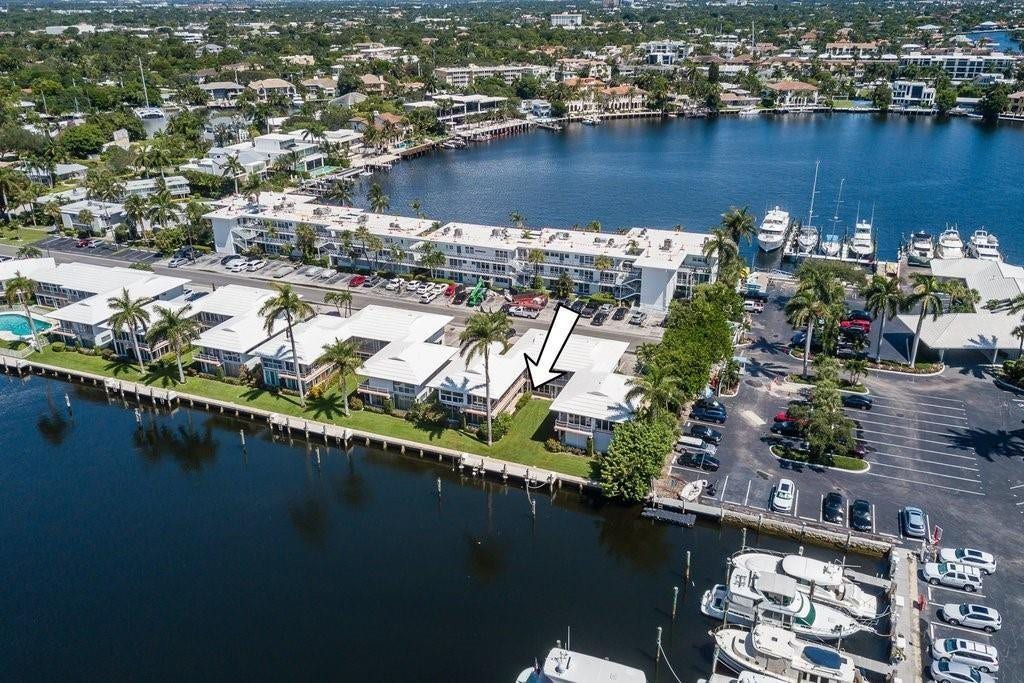 2760 YACHT CLUB Boulevard, #10C, Fort Lauderdale, Fort Lauderdale, FL 33304 Waterfront property featuring direct boat dock access with multiple vessel slips, expansive manicured lawn with mature palm landscaping, white metal-frame structures with covered outdoor spaces, concrete parking areas, and panoramic water frontage along a deep-water canal with neighboring residential and commercial properties visible across the waterway