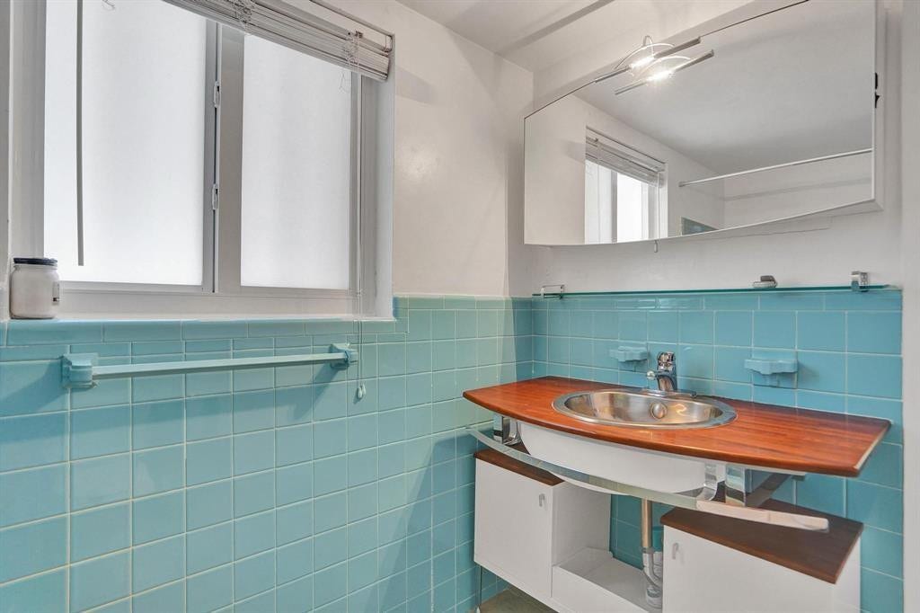 2760 YACHT CLUB Boulevard, #10C, Fort Lauderdale, Fort Lauderdale, FL 33304 Charming bathroom featuring turquoise tile walls, a custom wood-finish vanity with integrated dual sink basin, and chrome fixtures