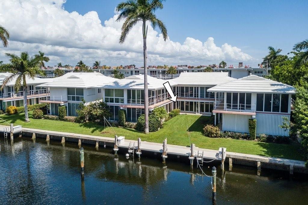 2760 YACHT CLUB Boulevard, #10C, Fort Lauderdale, Fort Lauderdale, FL 33304 Waterfront residence featuring modern architectural design with expansive glass paneling, elevated construction on pilings, manicured lawn with mature palm trees, private boat dock with dual slips, and panoramic water frontage along a navigable canal
