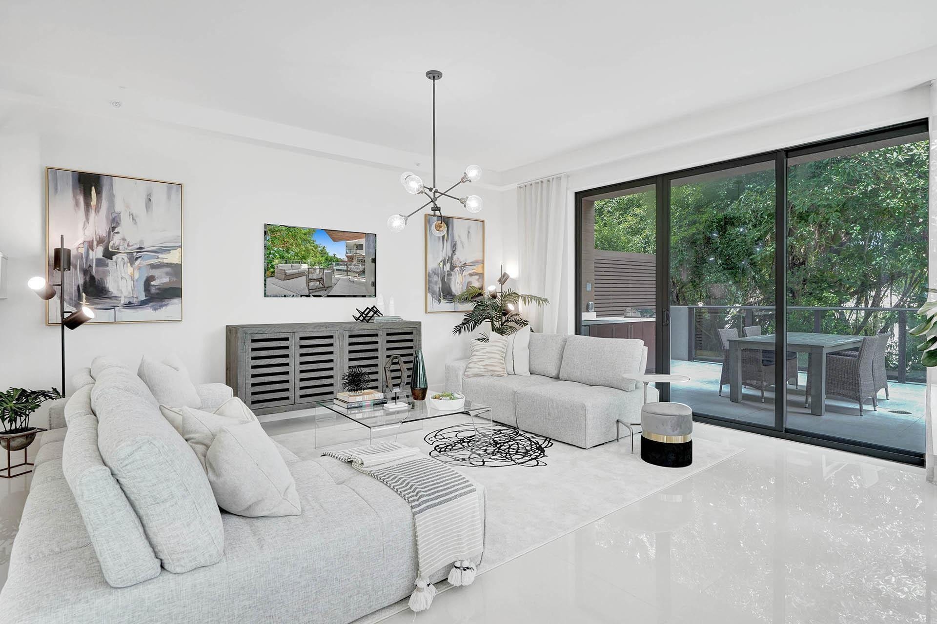 Bright, light-filled living room showcasing floor-to-ceiling glass doors and windows framing lush outdoor greenery