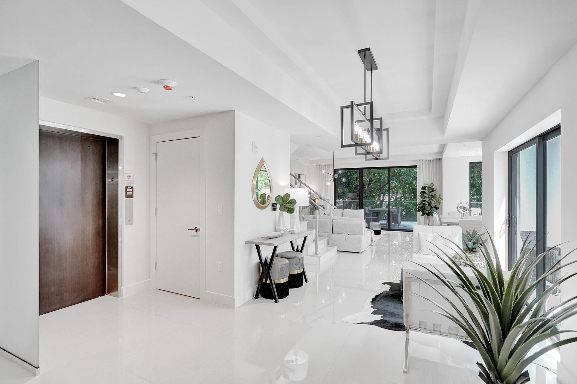 Bright, open-concept interior showcasing polished white flooring, soaring ceilings with geometric pendant lighting, and abundant natural light from multiple windows
