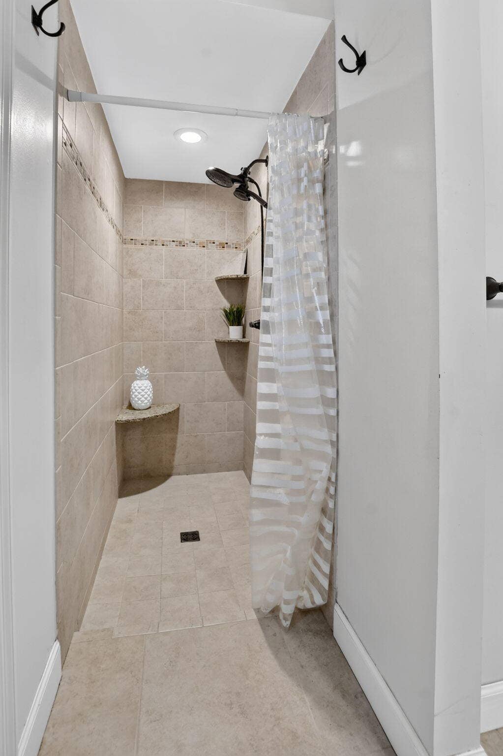 XL walk in shower with tile to the ceiling and pretty glass inlays. Two heads to wash away your worries.