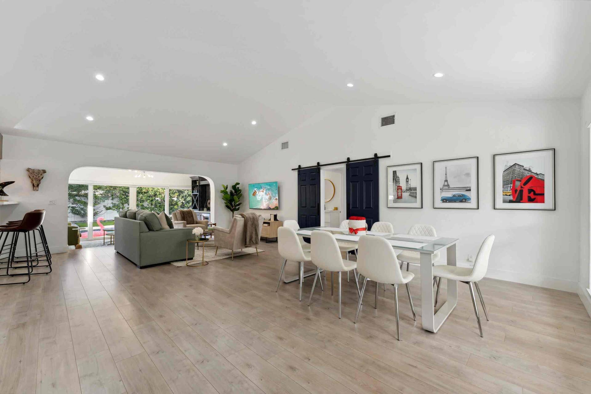 Open-concept living space showcasing wood-finish flooring, recessed ceiling lighting, and abundant natural light from large windows