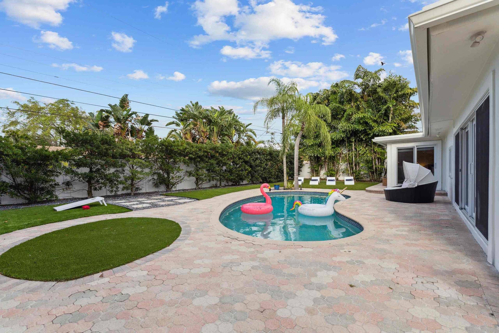 Expansive backyard oasis featuring a resort-style saltwater pool with integrated spa, circular lounge area, and travertine-look pavers