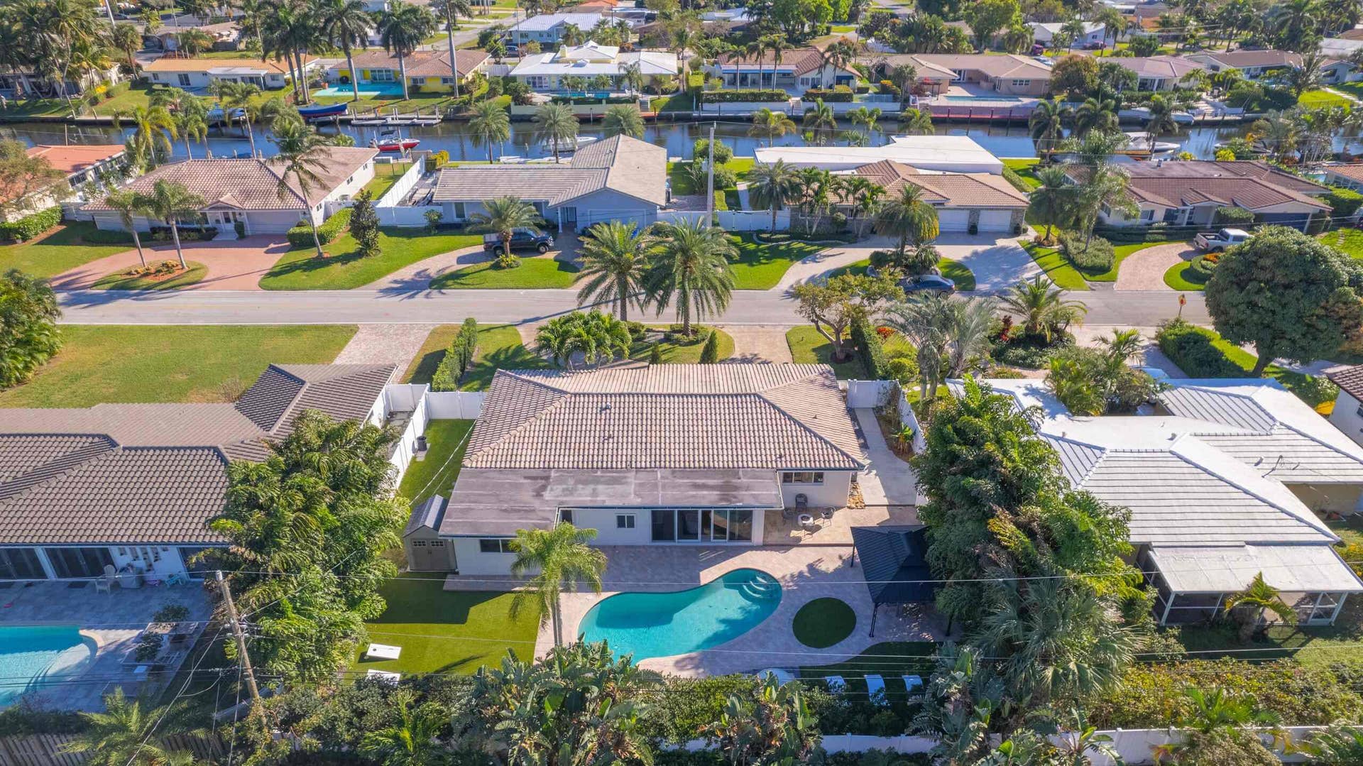 Residential property featuring a swimming pool, mature landscaping, and a tile roof