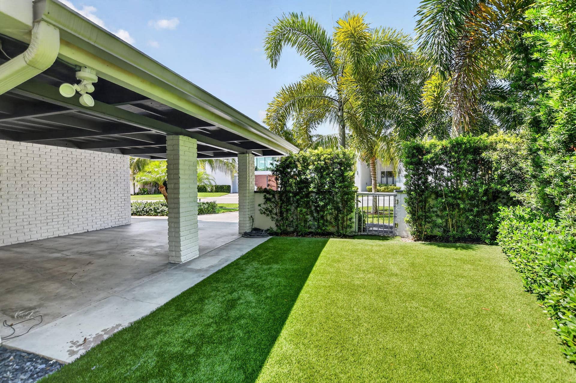 This is the West side elevation of the Carport, the yard is partially fenced in . The side and rear yards have recently installed artificial turf, no need for a mower, sprinklers, or fertilizer! Safe for children and pets too!