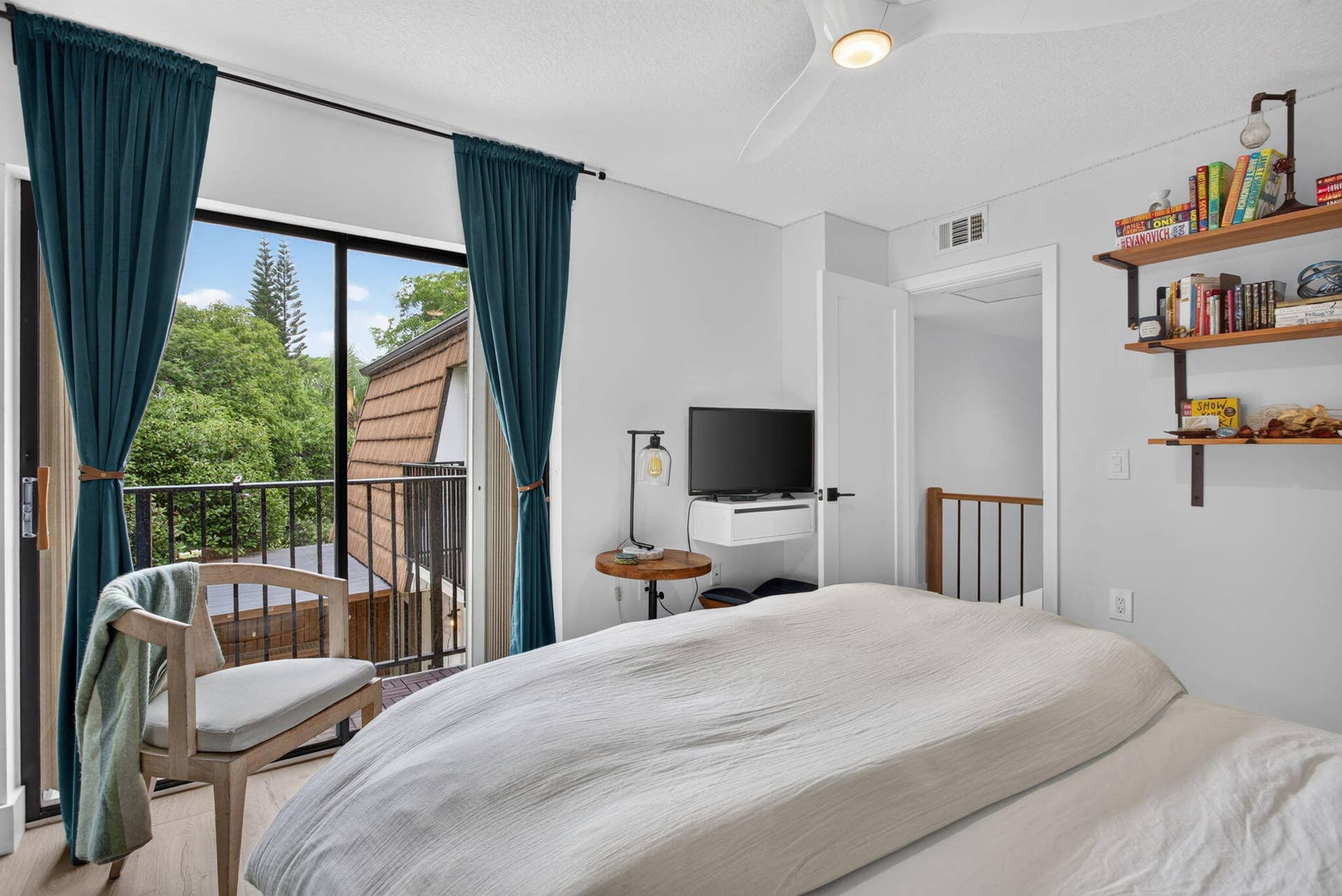 9113 SW 20th Court, #A, Davie, FL 33324 Sliding glass door opening to an exterior balcony, wood-finish flooring, ceiling fan, and built-in shelving with metal brackets