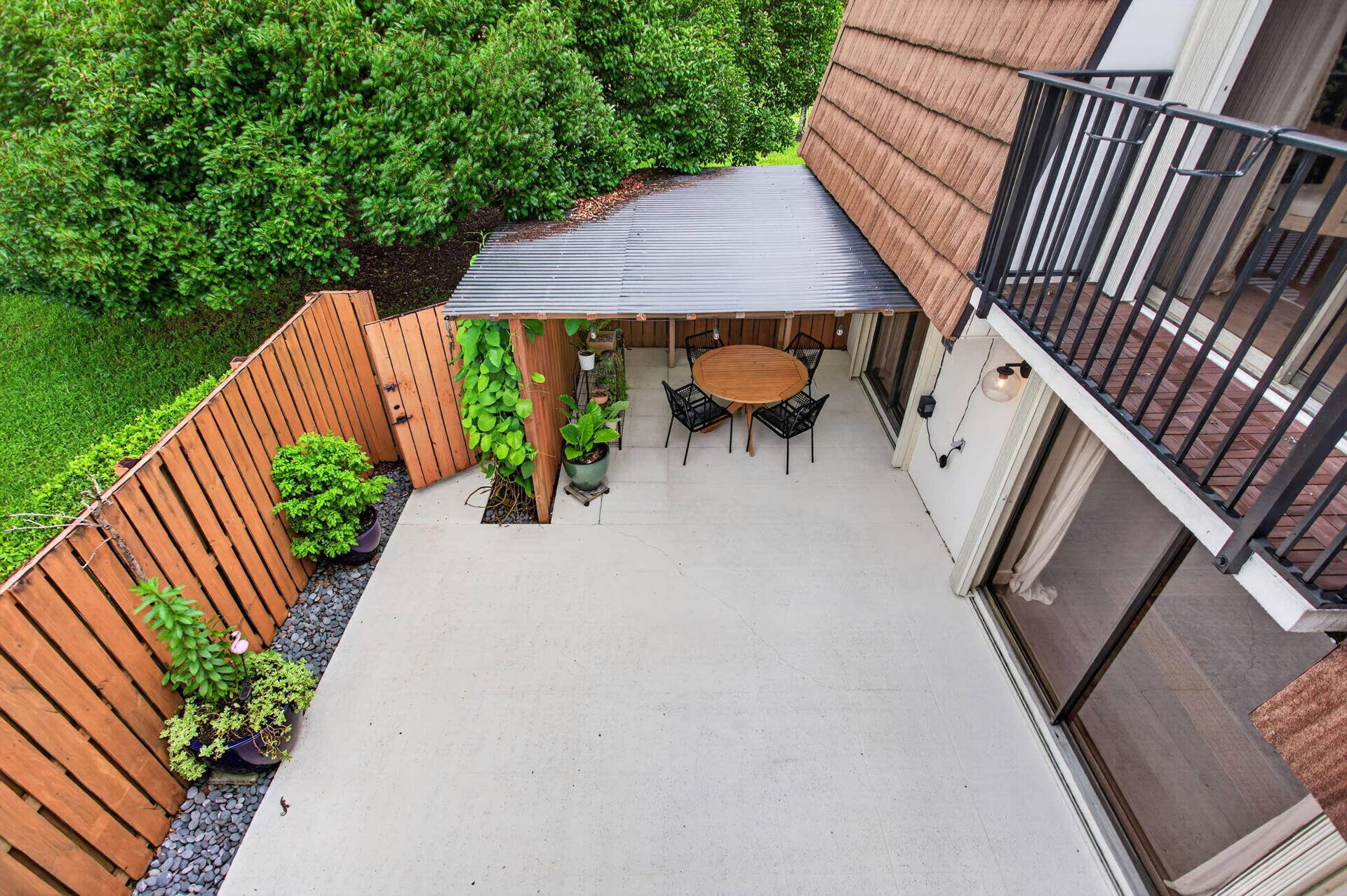 9113 SW 20th Court, #A, Davie, FL 33324 Private outdoor patio featuring a wooden privacy fence, a covered dining area, and a second-story balcony with metal railings
