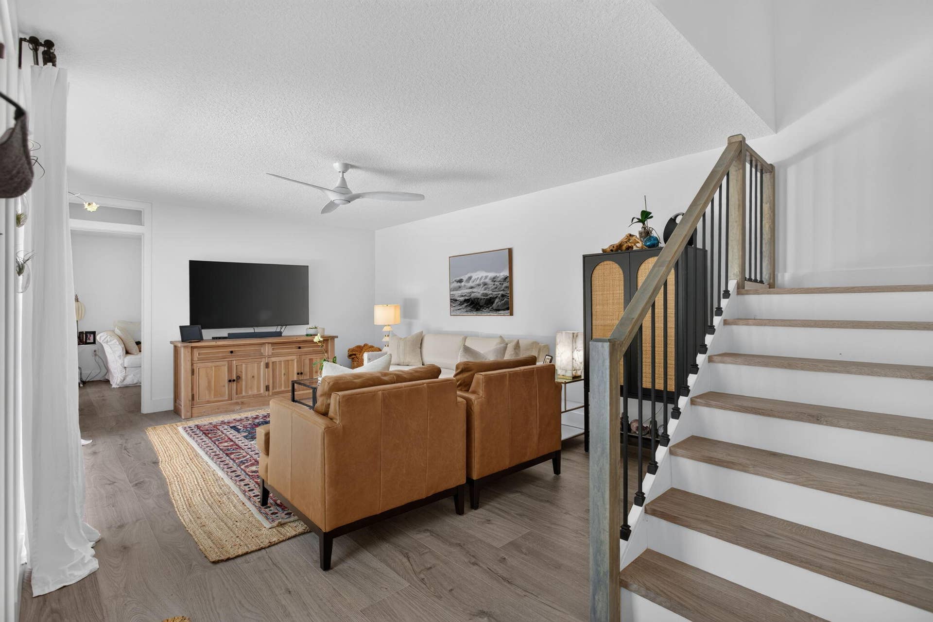 9113 SW 20th Court, #A, Davie, FL 33324 Wood-finish flooring throughout, modern ceiling fan, staircase with wood and metal railing, and built-in media console