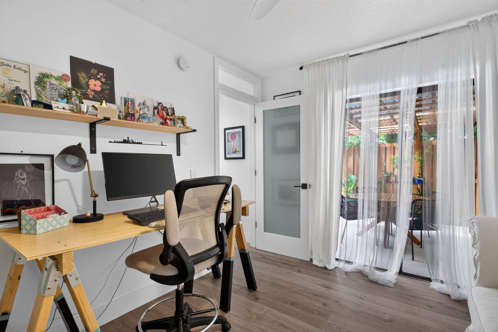 9113 SW 20th Court, #A, Davie, FL 33324 Wood-finish flooring, built-in shelving, white walls, and a glass-paneled door opening to an outdoor patio with a pergola