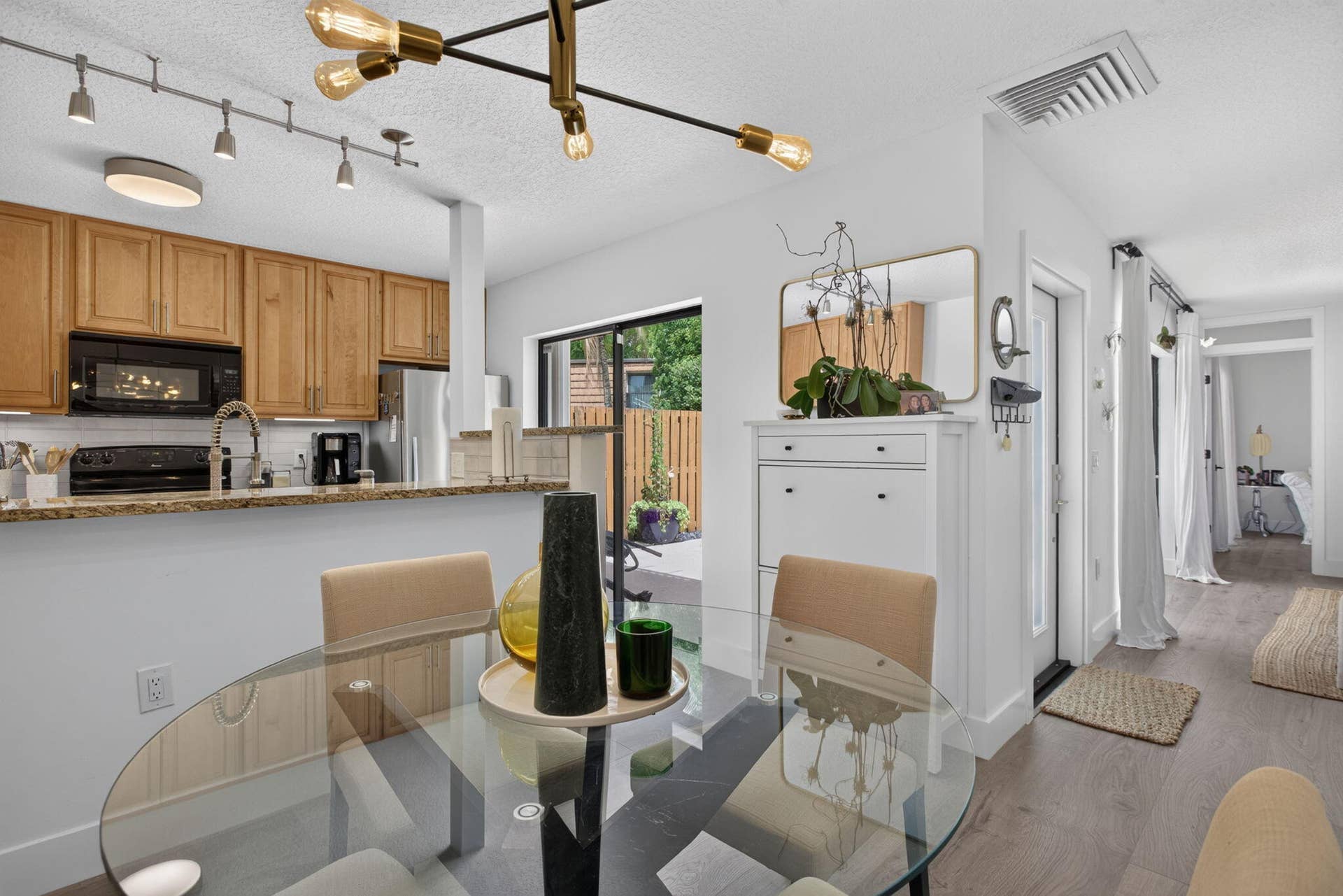9113 SW 20th Court, #A, Davie, FL 33324 Open-concept living space featuring wood-finish flooring, a kitchen with wood cabinetry and stainless steel appliances, and a sliding glass door leading to an outdoor area