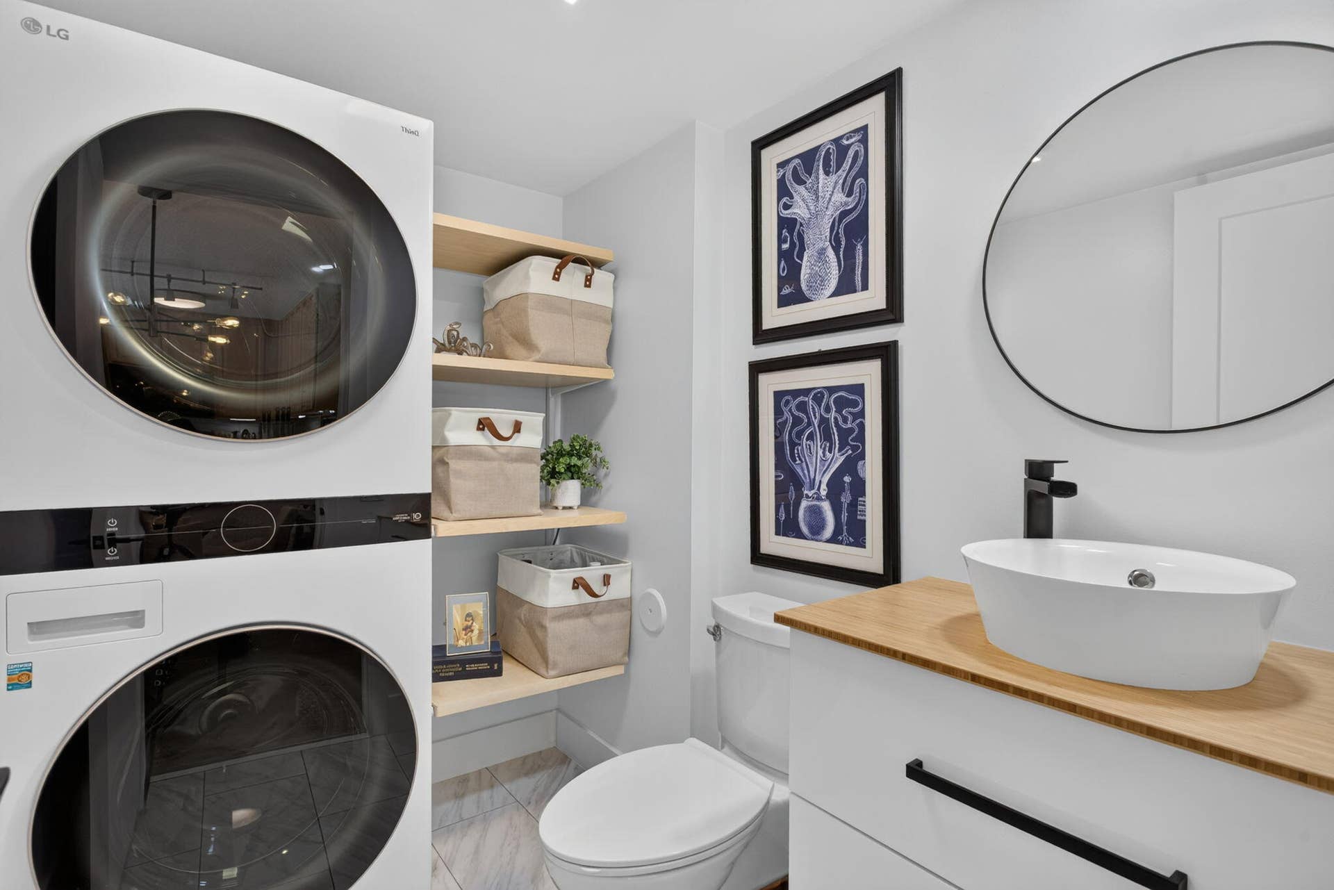 9113 SW 20th Court, #A, Davie, FL 33324 Stacked washer and dryer, open shelving, wall-mounted oval mirror, vessel sink with a black faucet, and a light wood-finish countertop