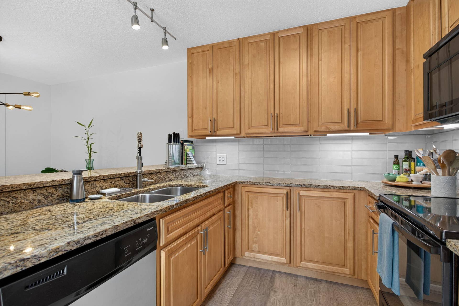 9113 SW 20th Court, #A, Davie, FL 33324 Kitchen featuring light wood cabinetry, granite countertops, a double basin stainless steel sink, a tile backsplash, and wood-finish flooring
