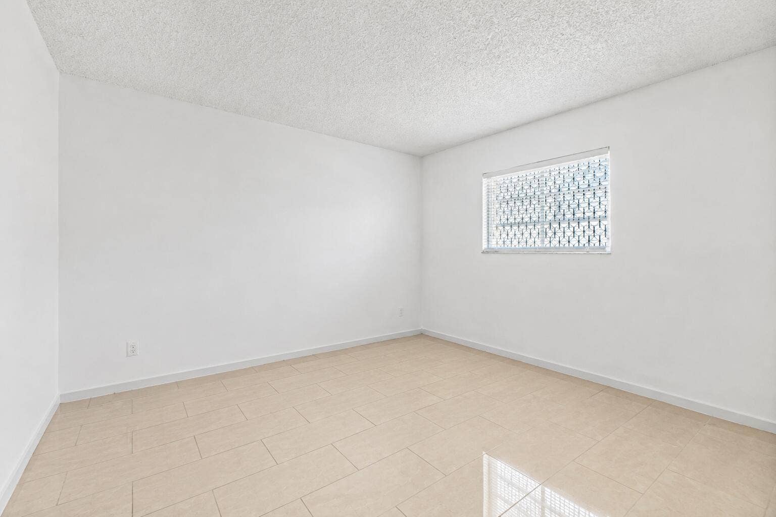 Bright, light-filled room featuring ceramic tile flooring, and clean white walls