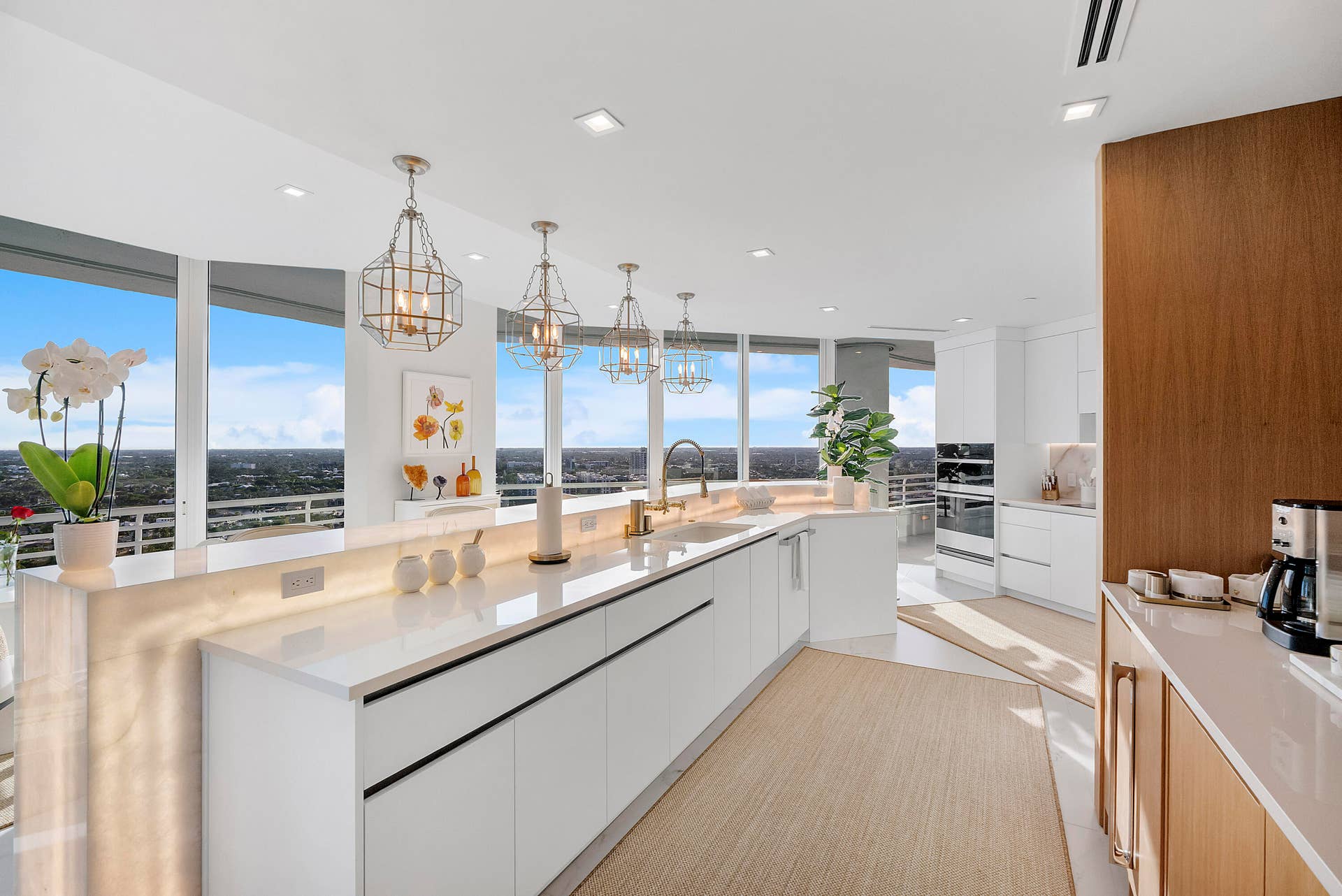 1700 S OCEAN Boulevard, #PH B-D, Lauderdale By The Sea, FL 33062 A true culinary masterpiece, this world-class chef's kitchen showcases bespoke White Oak cabinetry, sleek high-gloss white cabinetry, luxurious glossy quartz countertops, and a breathtaking backlit Cristello natural stone island that glows beneath exquisite golden pendant chandeliers. Designed for the discerning chef and effortless entertaining alike, this extraordinary space seamlessly blends architectural beauty, exceptional craftsmanship, and panoramic ocean vistas into one unforgettable experience.