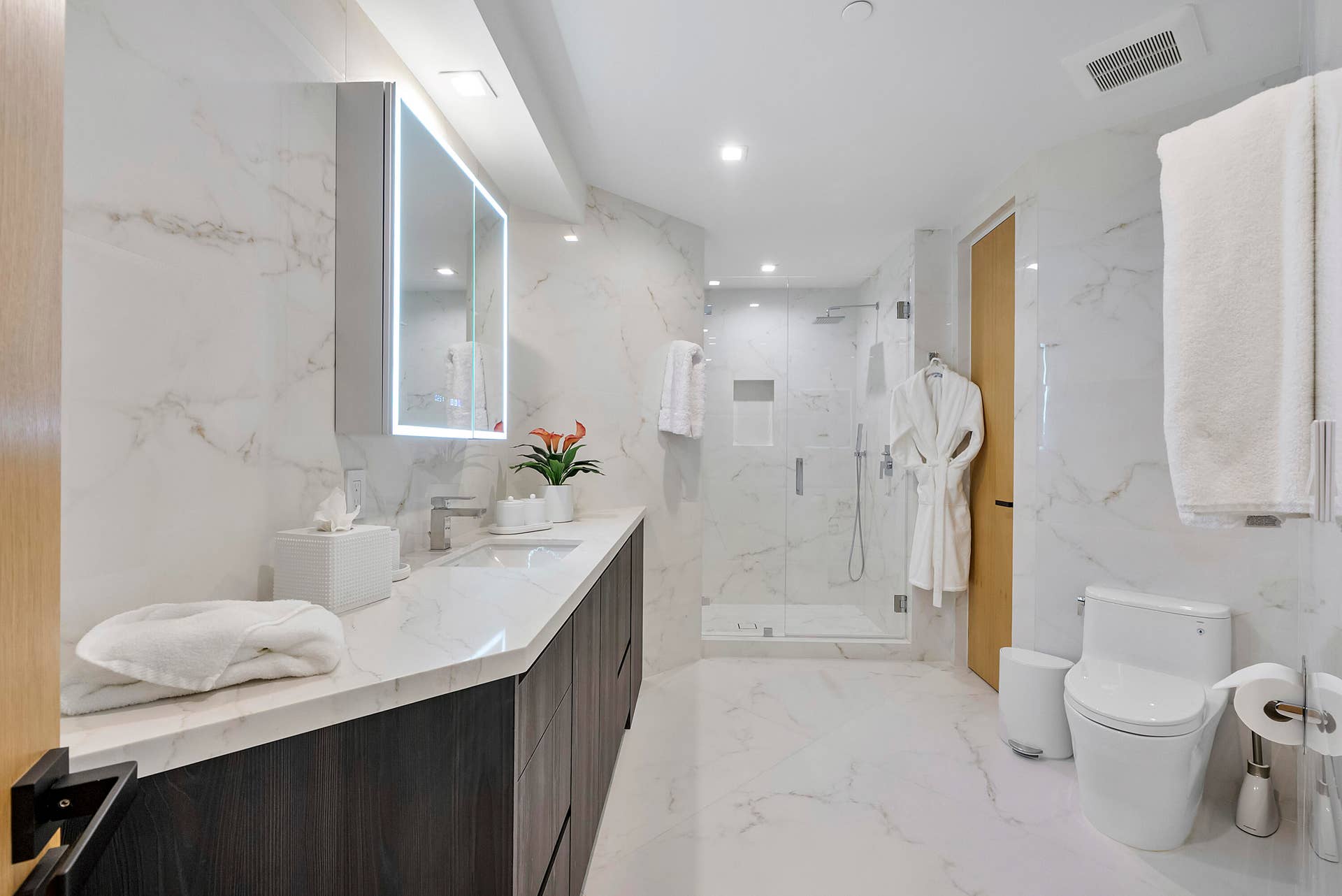 1700 S OCEAN Boulevard, #PH B-D, Lauderdale By The Sea, FL 33062 The Mandarin Rooms beautifully appointed private en-suite bath offers a serene counterpoint to the suites vibrant palette, enveloped in luminous marble-look surfaces with an expansive vanity, illuminated mirror and glass-enclosed shower creating a crisp, sophisticated spa-like retreat exclusively for guests.