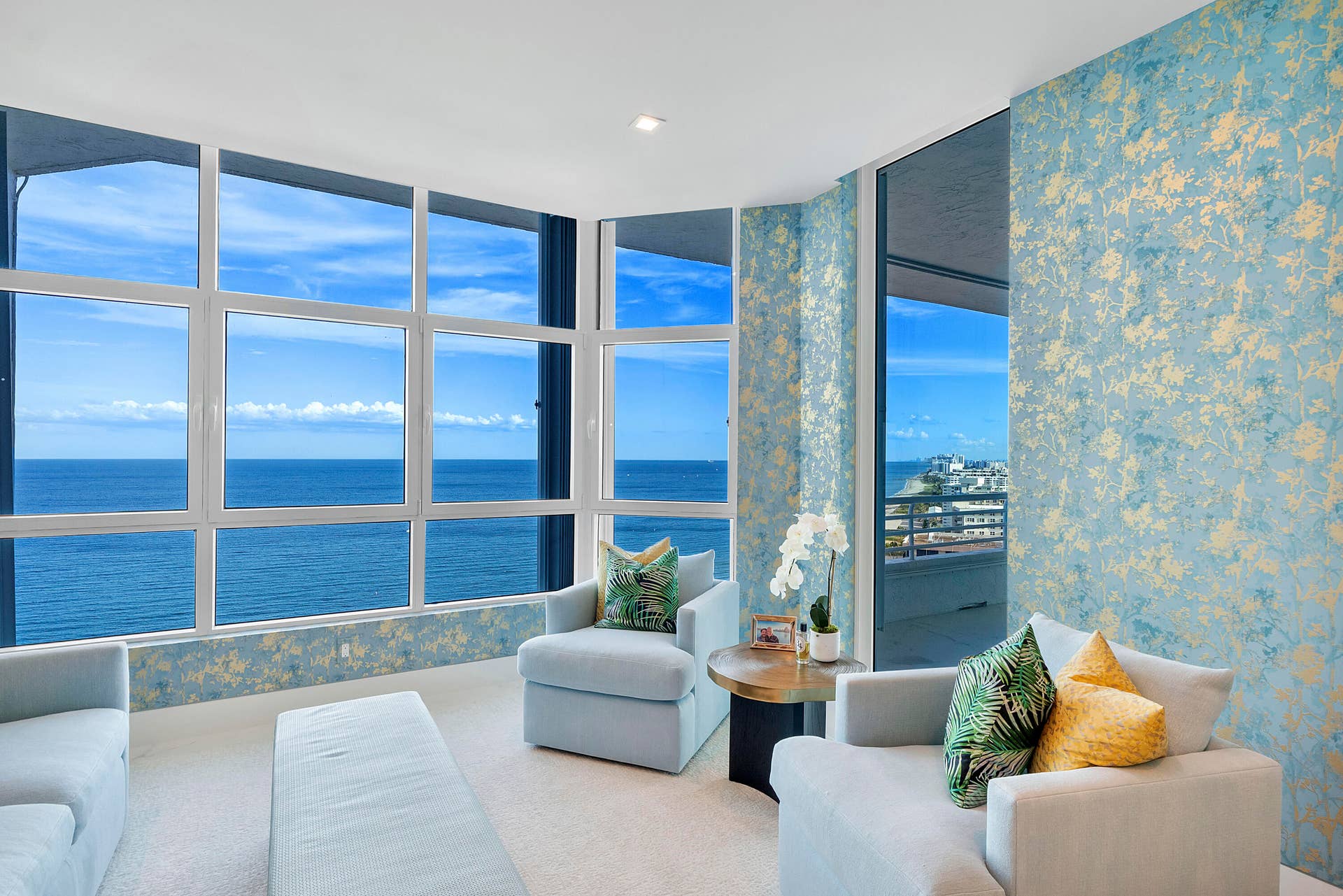 1700 S OCEAN Boulevard, #PH B-D, Lauderdale By The Sea, FL 33062 This room tells a story. The wallpaper doesn't compete with the oceanit complements it. The soft blues and gold accents echo the colors of the sea and sky, creating a seamless connection between the interior and the landscape beyond. The custom decorative golden screens also act as a graceful transition between spaces, adding privacy while maintaining the open flow of the residence.