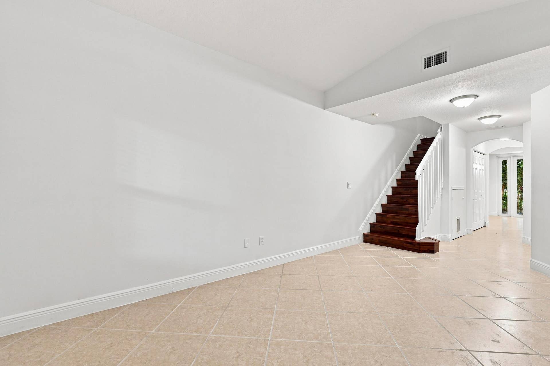 2107 Anchor Court, Fort Lauderdale, FL 33312 Spacious living area just off the front entry featuring tile flooring, high ceilings, and an open layout that flows seamlessly toward the kitchen and dining areas. A wood staircase adds warmth and character while leading to the second floor.