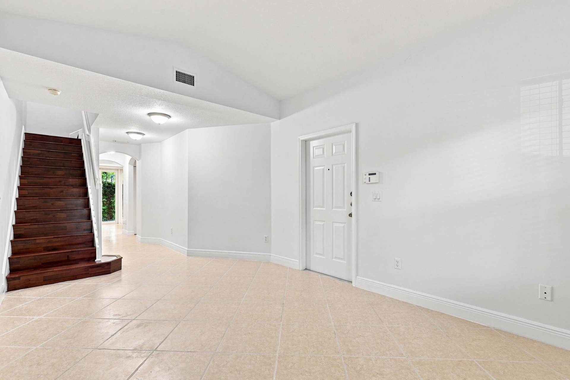 2107 Anchor Court, Fort Lauderdale, FL 33312 Spacious living area just off the front entry featuring tile flooring, high ceilings, and an open layout that flows seamlessly toward the kitchen and dining areas. A wood staircase adds warmth and character while leading to the second floor.