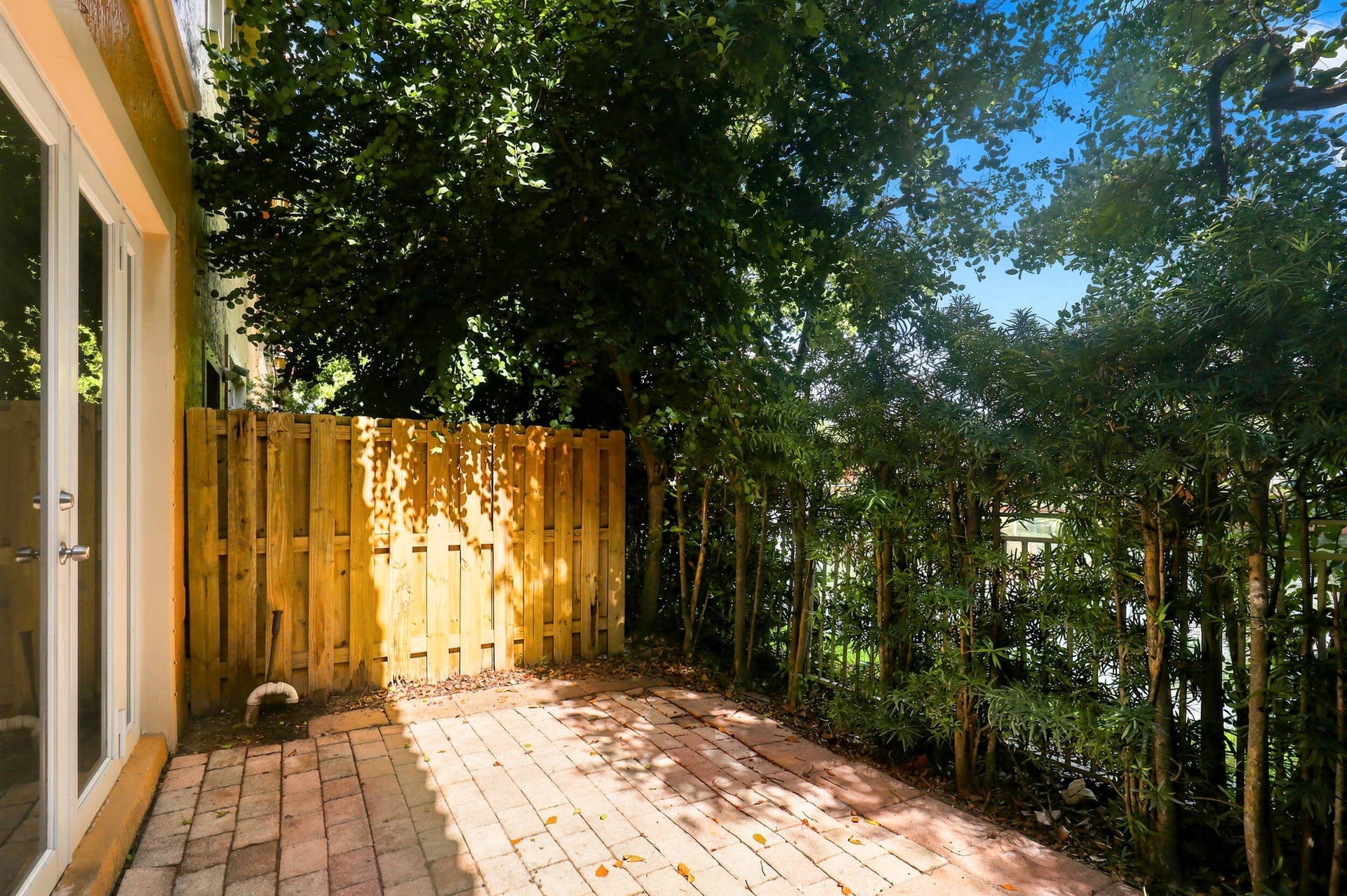 2107 Anchor Court, Fort Lauderdale, FL 33312 Private brick-paver patio surrounded by mature tropical landscaping, offering a peaceful, shaded outdoor space with direct access from the home.