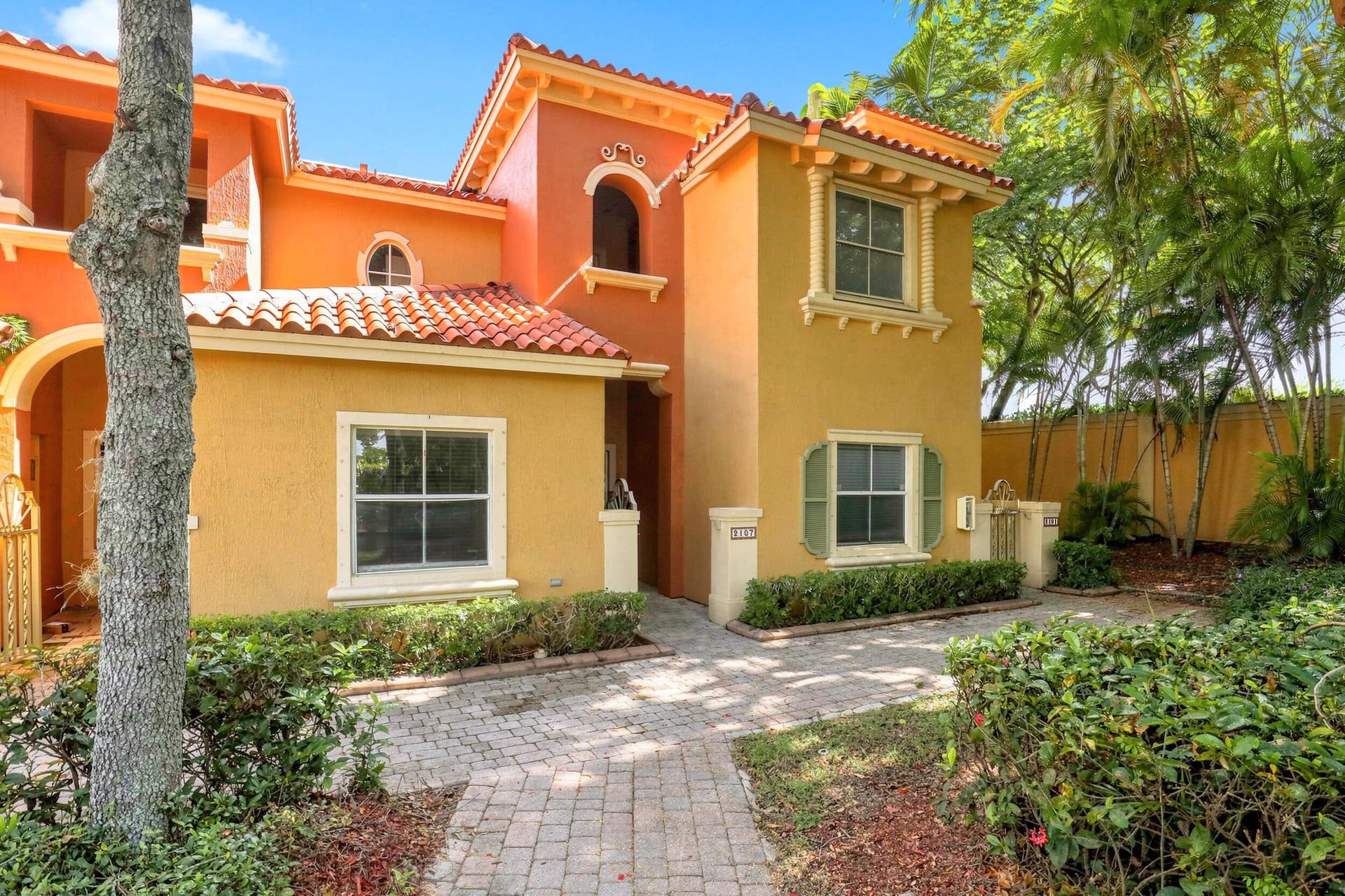 2107 Anchor Court, Fort Lauderdale, FL 33312 Attractive Mediterranean inspired townhouse surrounded by mature tropical landscaping, featuring a charming paver walkway and welcoming covered entry.