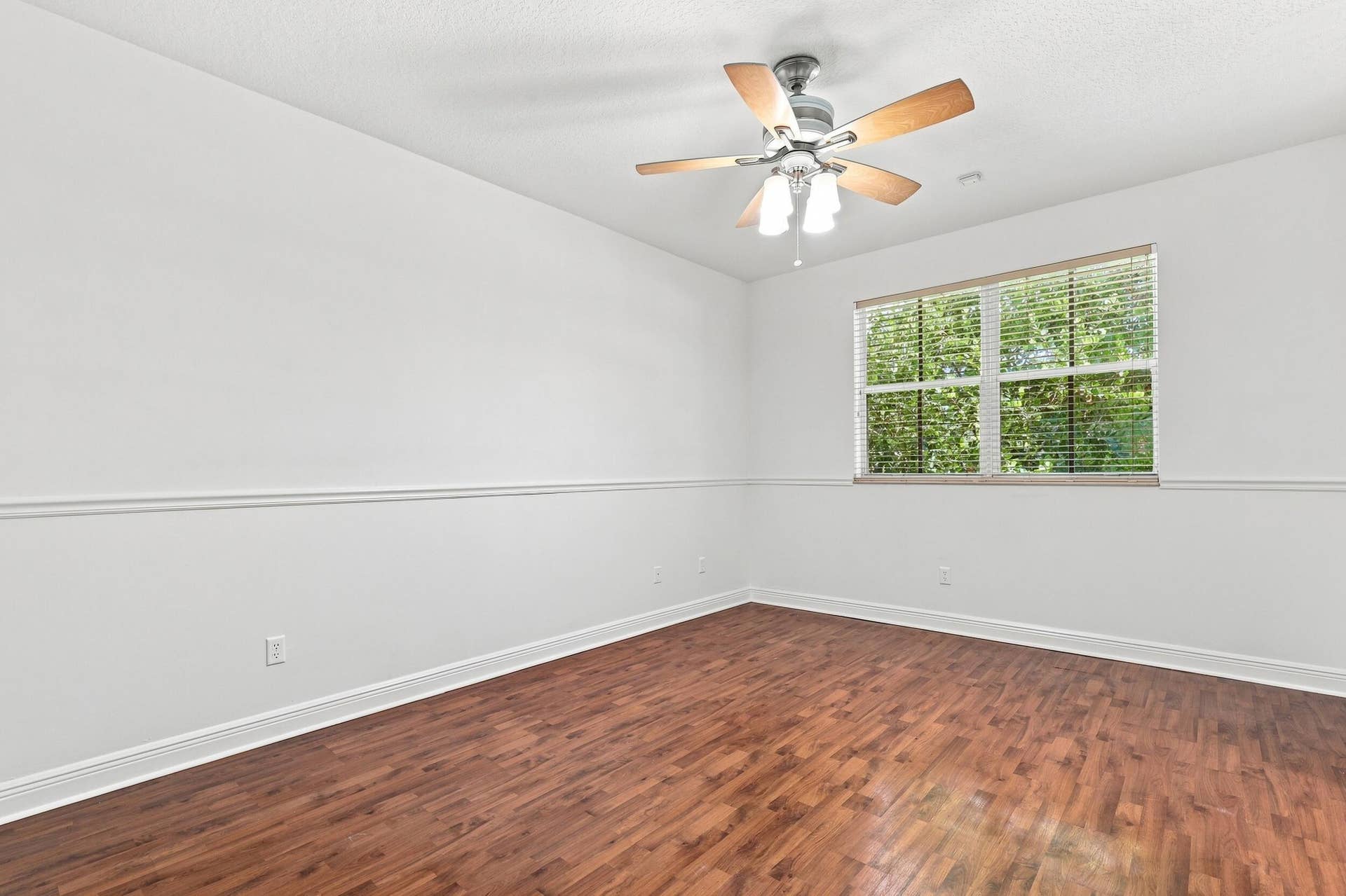 2107 Anchor Court, Fort Lauderdale, FL 33312 Spacious primary suite featuring warm wood flooring, abundant natural light, a large window overlooking lush greenery, and direct access to the private ensuite bathroom. The generous layout provides plenty of space and creates a comfortable private retreat.