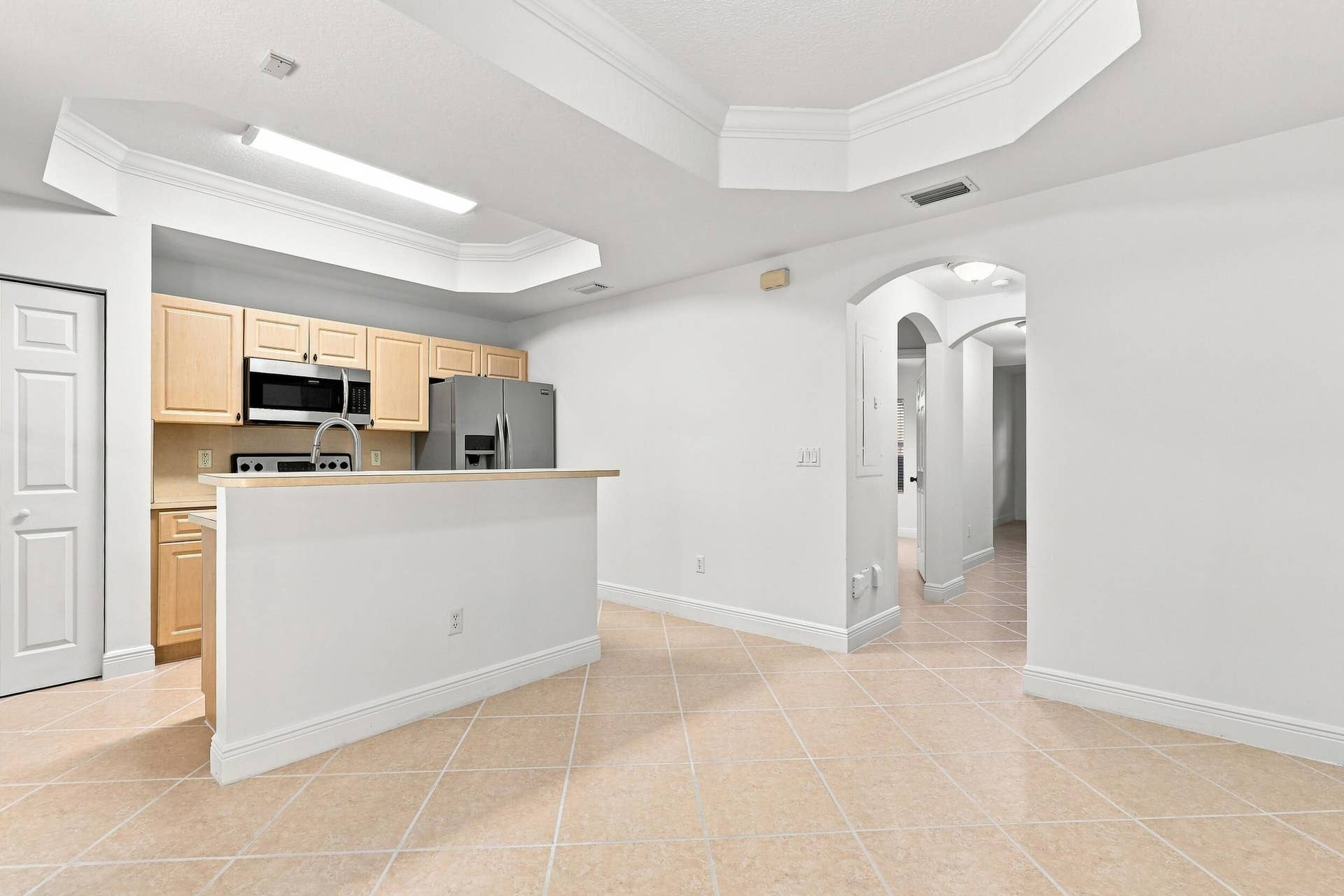 2107 Anchor Court, Fort Lauderdale, FL 33312 Bright dining area featuring tile flooring, a decorative tray ceiling with crown molding, and French doors that bring in natural light and provide direct access to the private outdoor patio. The open layout connects seamlessly with the kitchen for easy everyday living and entertaining.