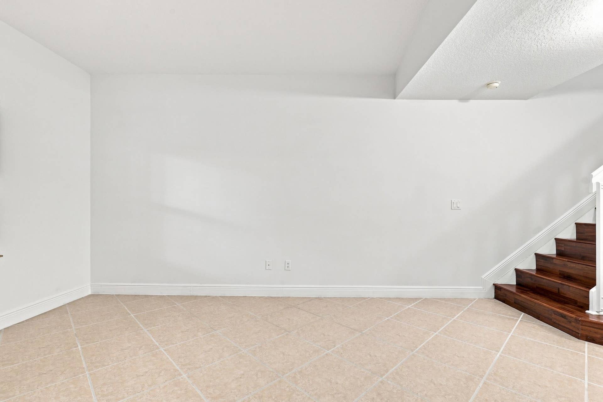 2107 Anchor Court, Fort Lauderdale, FL 33312 Spacious living area just off the front entry featuring tile flooring, high ceilings, and an open layout that flows seamlessly toward the kitchen and dining areas. A wood staircase adds warmth and character while leading to the second floor.