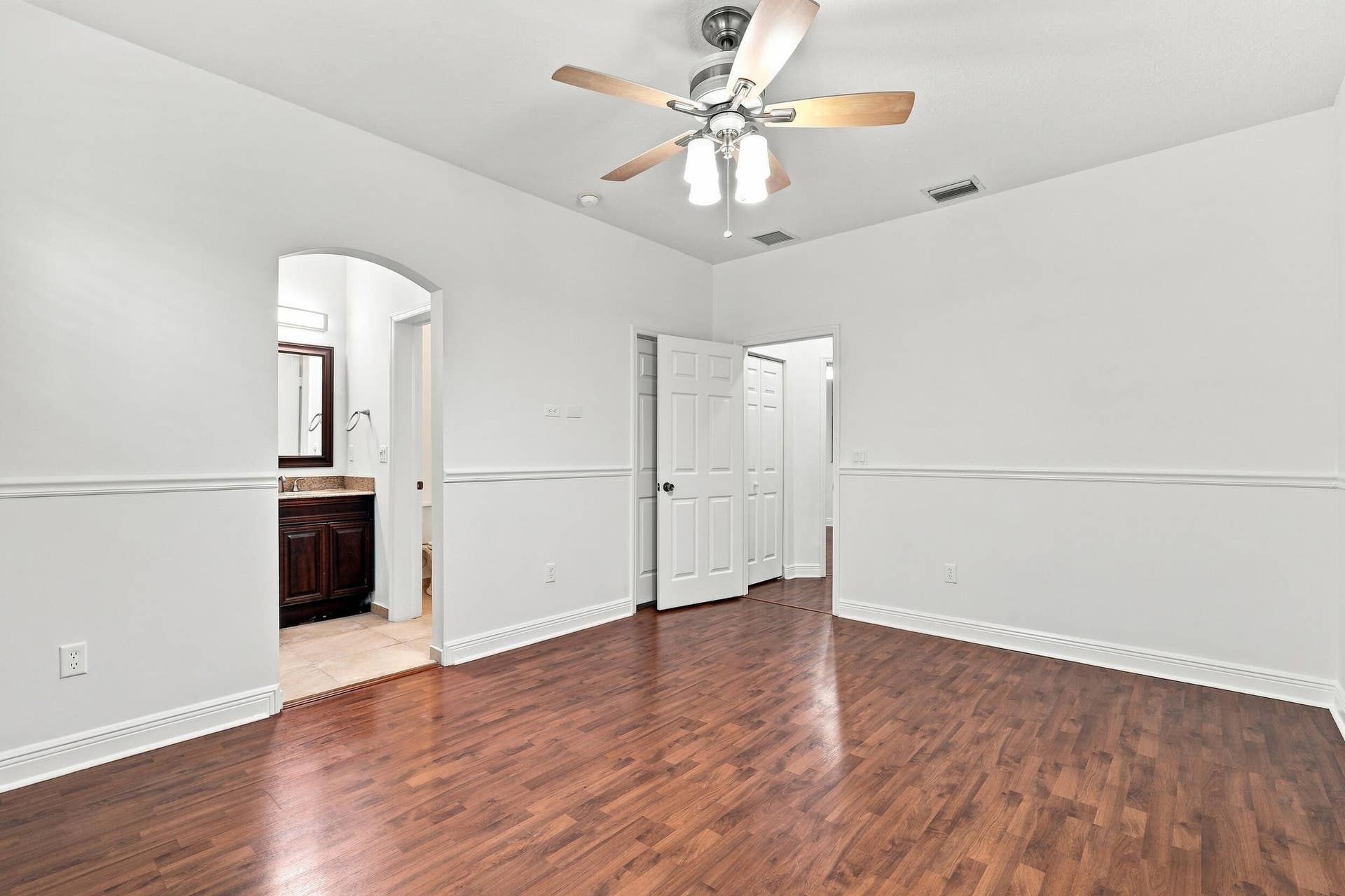 2107 Anchor Court, Fort Lauderdale, FL 33312 Spacious primary suite featuring warm wood flooring, abundant natural light, a large window overlooking lush greenery, and direct access to the private ensuite bathroom. The generous layout provides plenty of space and creates a comfortable private retreat.