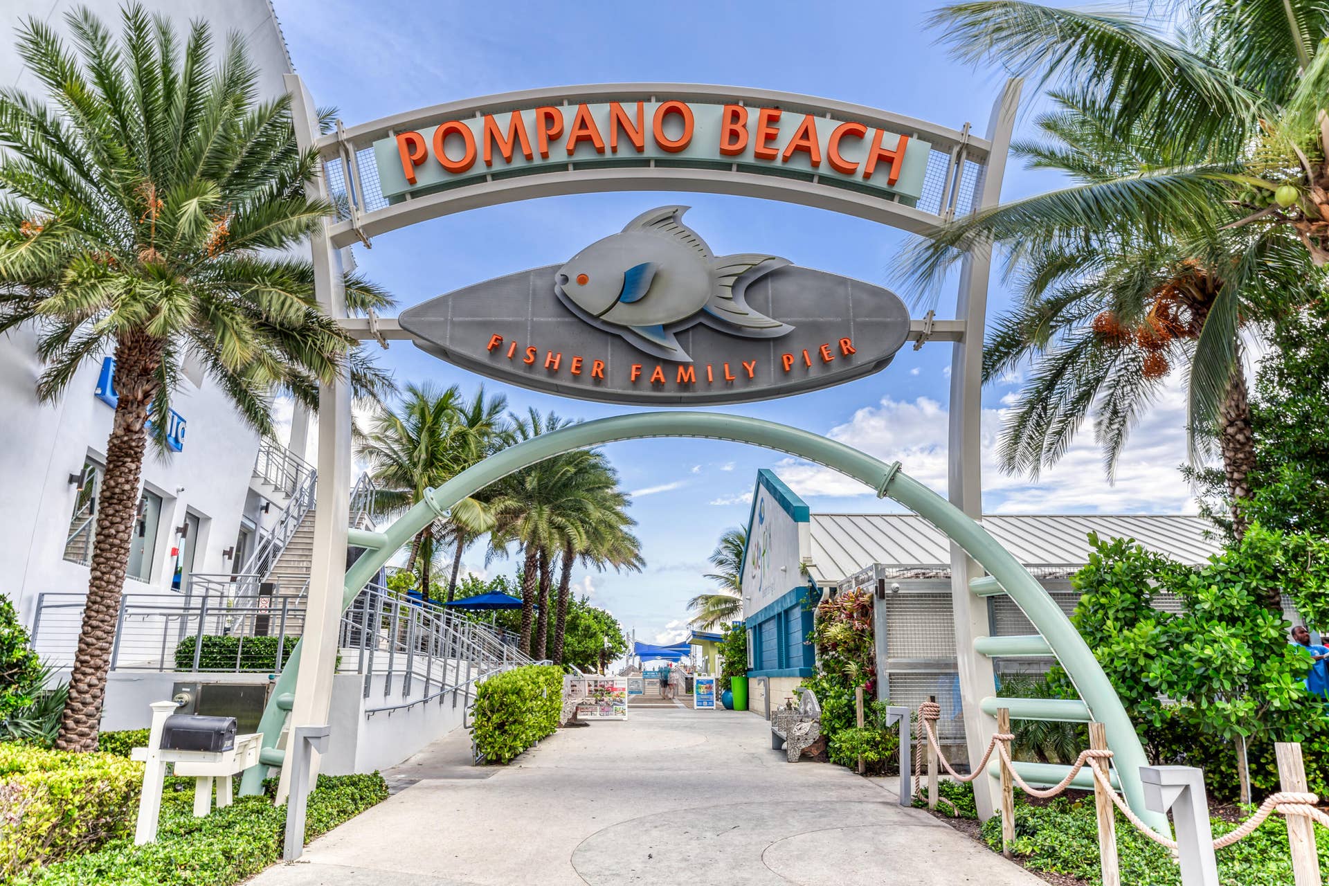 3224 NE 4th Street, Pompano Beach, FL 33062 Pompano Beach entrance archway featuring a paved walkway, lush landscaping, and prominent palm trees