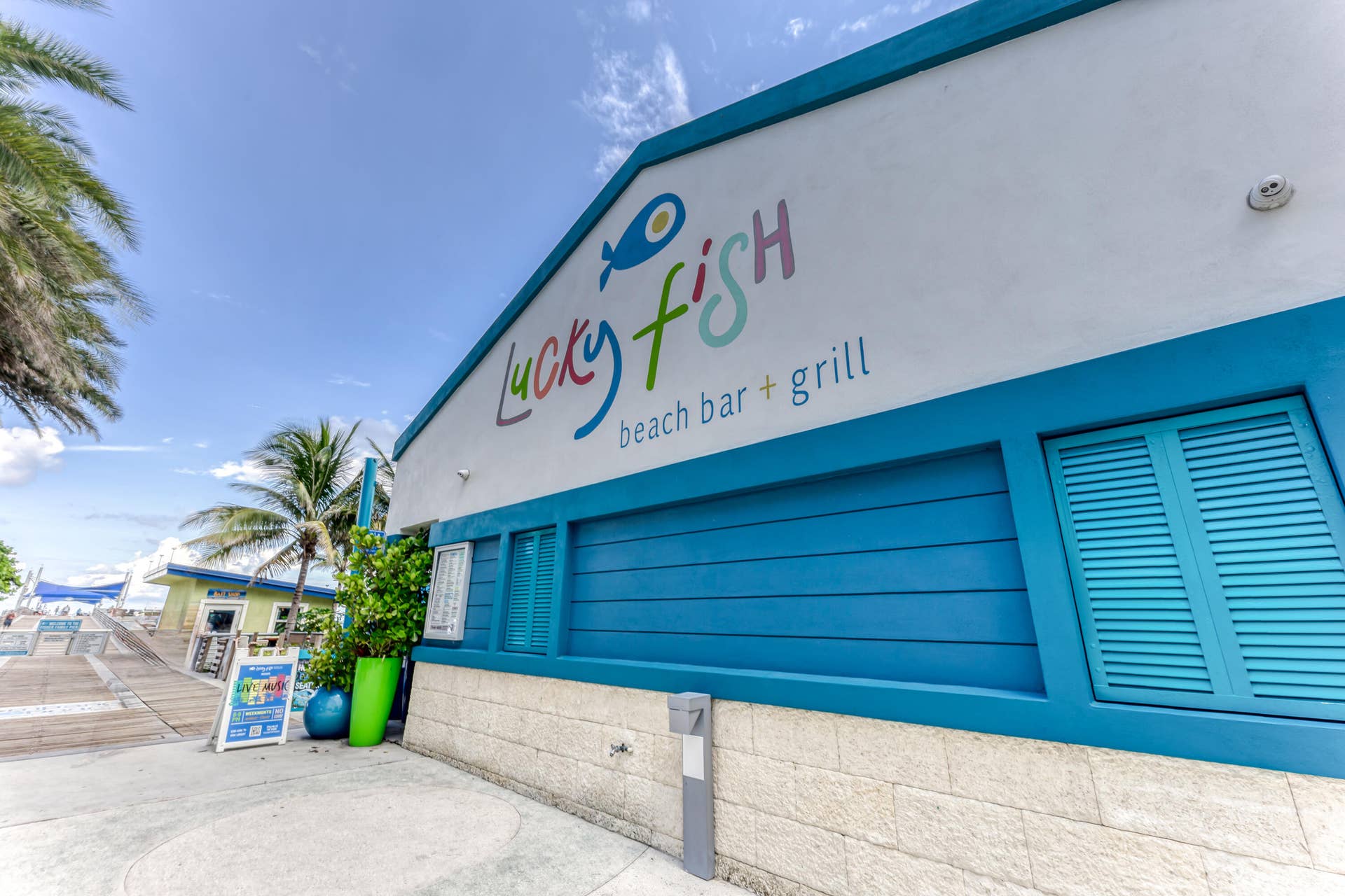 3224 NE 4th Street, Pompano Beach, FL 33062 Building exterior featuring blue horizontal siding, white signage with colorful lettering, and a light-colored stone-finish foundation