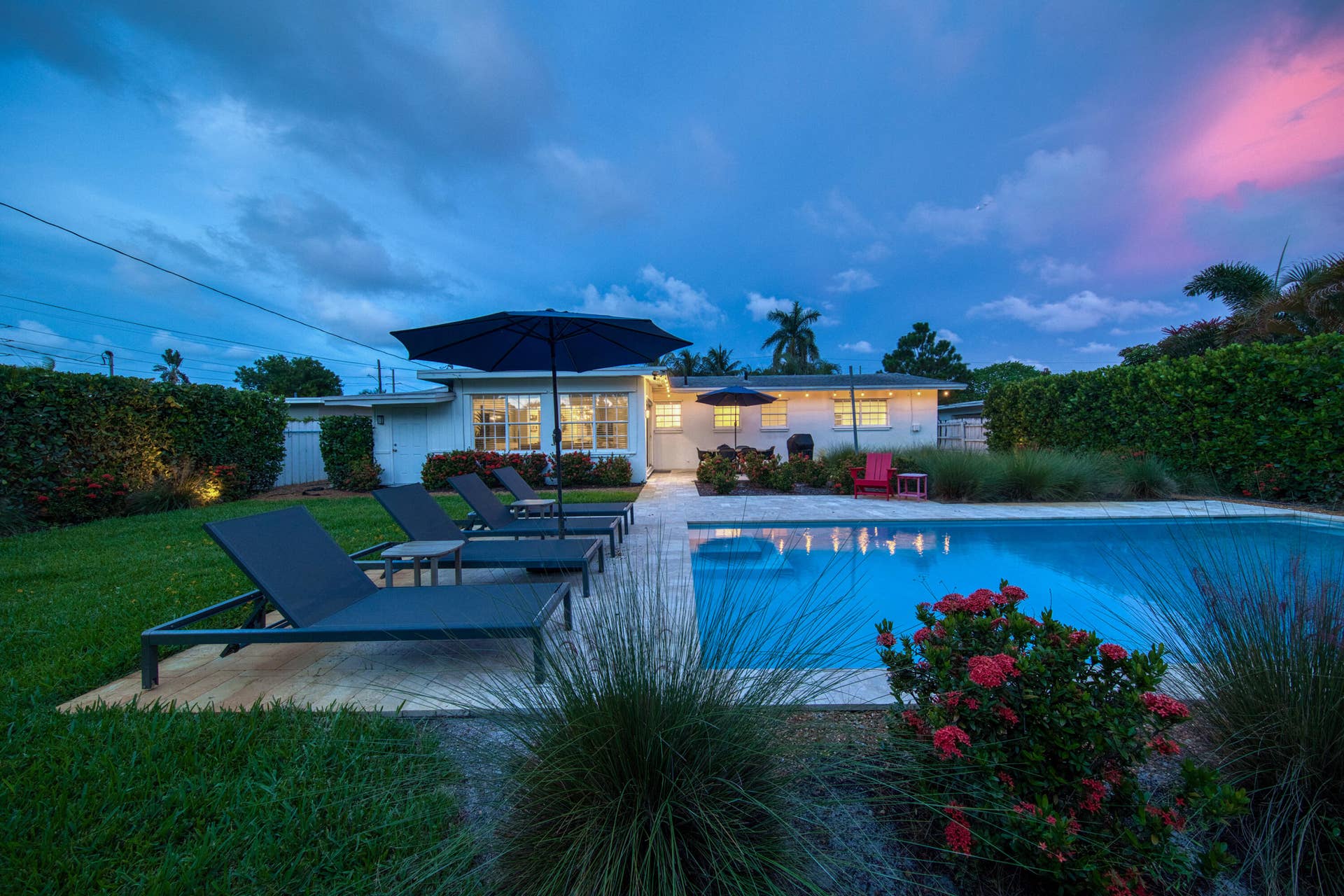 Expansive backyard featuring a rectangular swimming pool, concrete pool deck, and manicured lawn