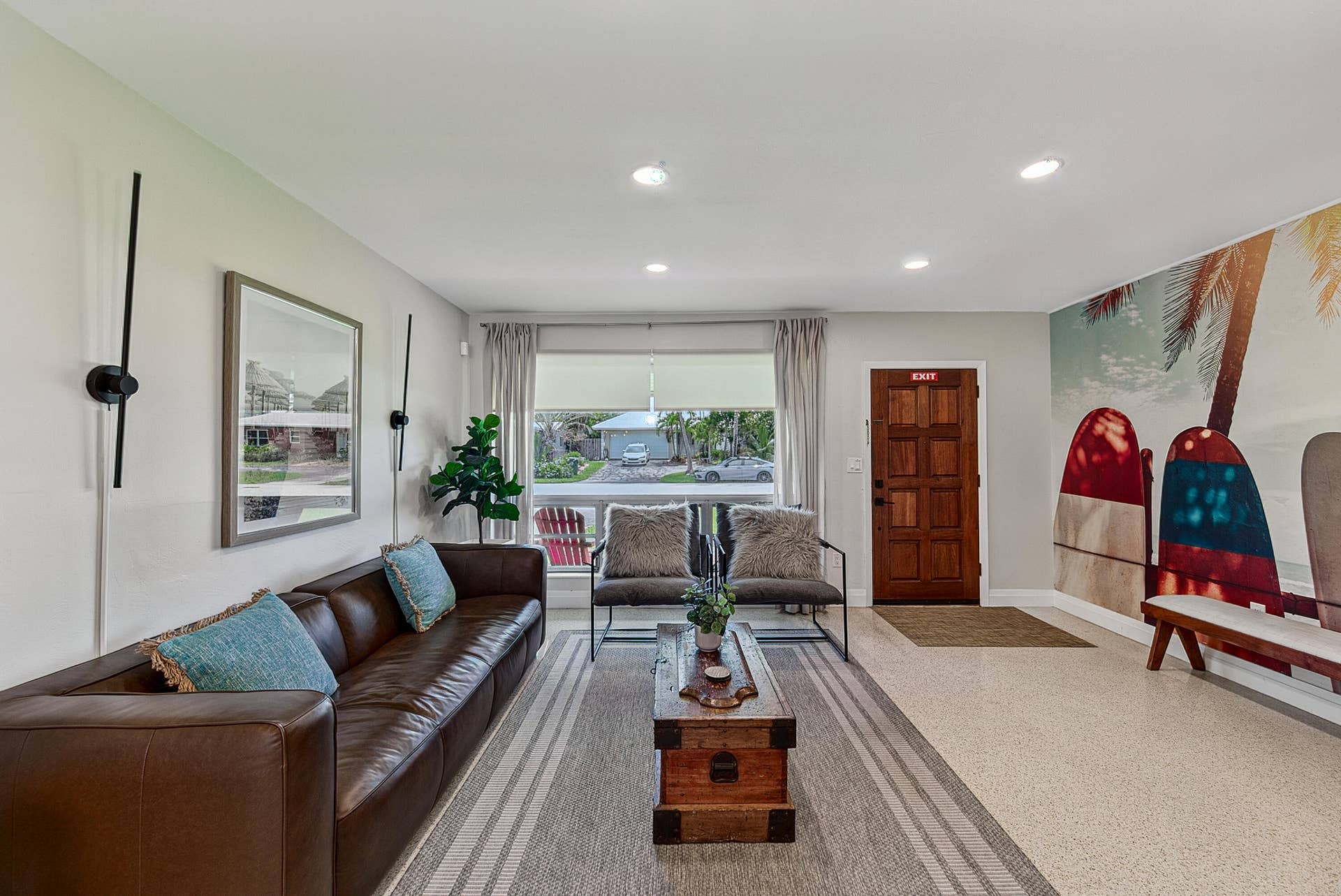 Recessed lighting, wood-finish panel door, wall-mounted light fixtures, window with roller shade, and wood-finish coffee table