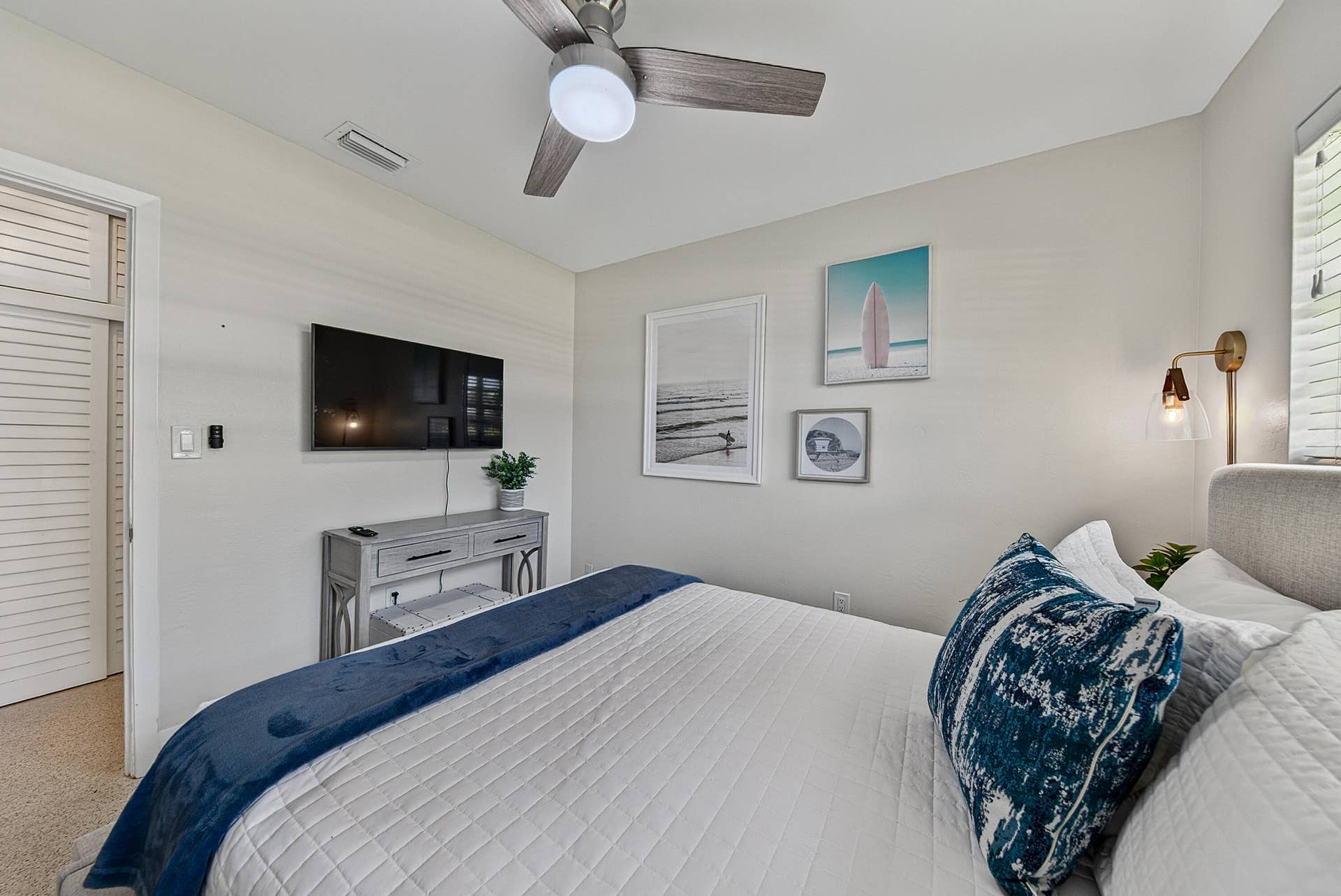 Ceiling-mounted fan, wall-mounted television, built-in wall sconce, and louvered bifold door