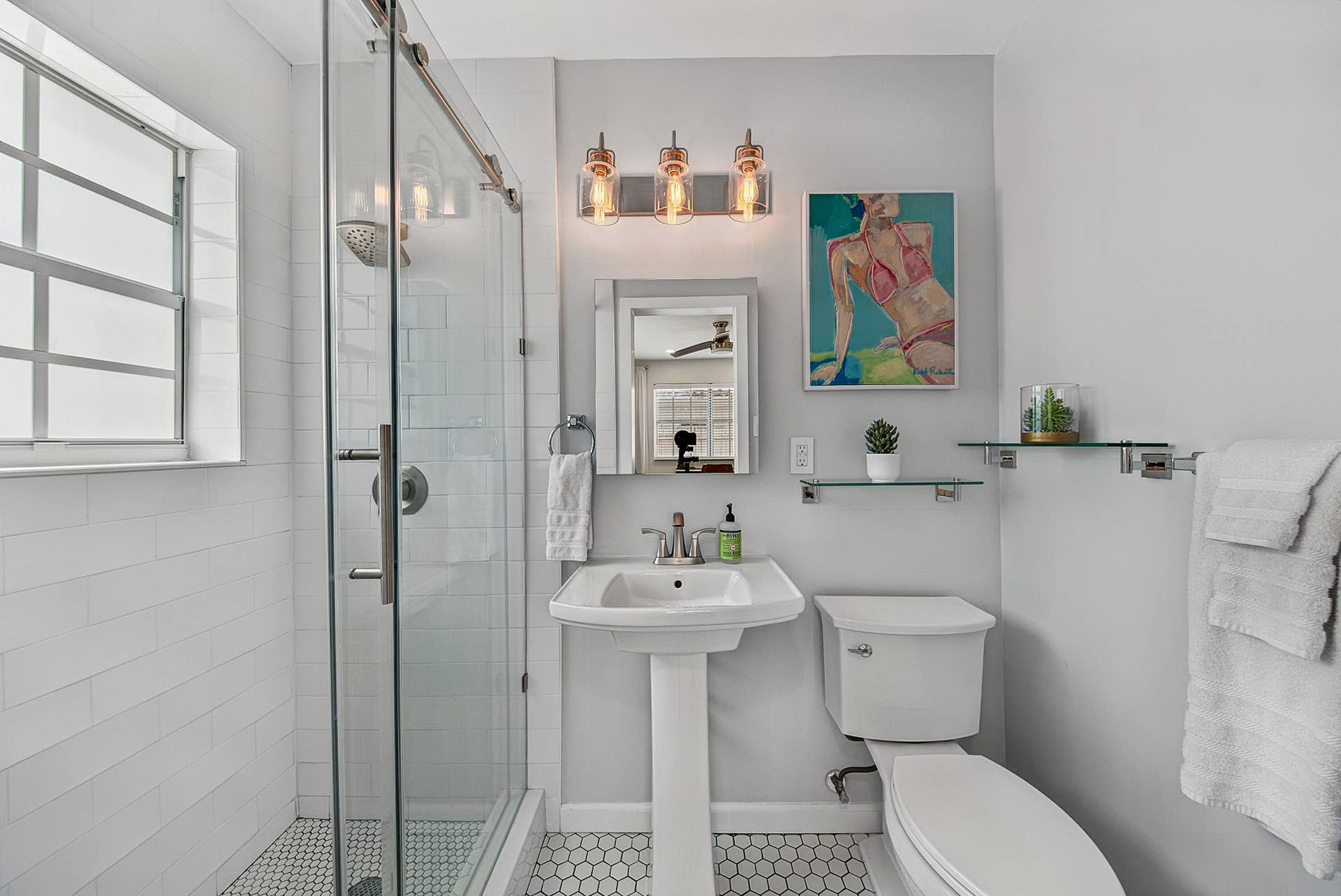 Spa-inspired bathroom featuring a walk-in shower with glass enclosure and tile surround, pedestal sink, toilet, and mosaic tile flooring