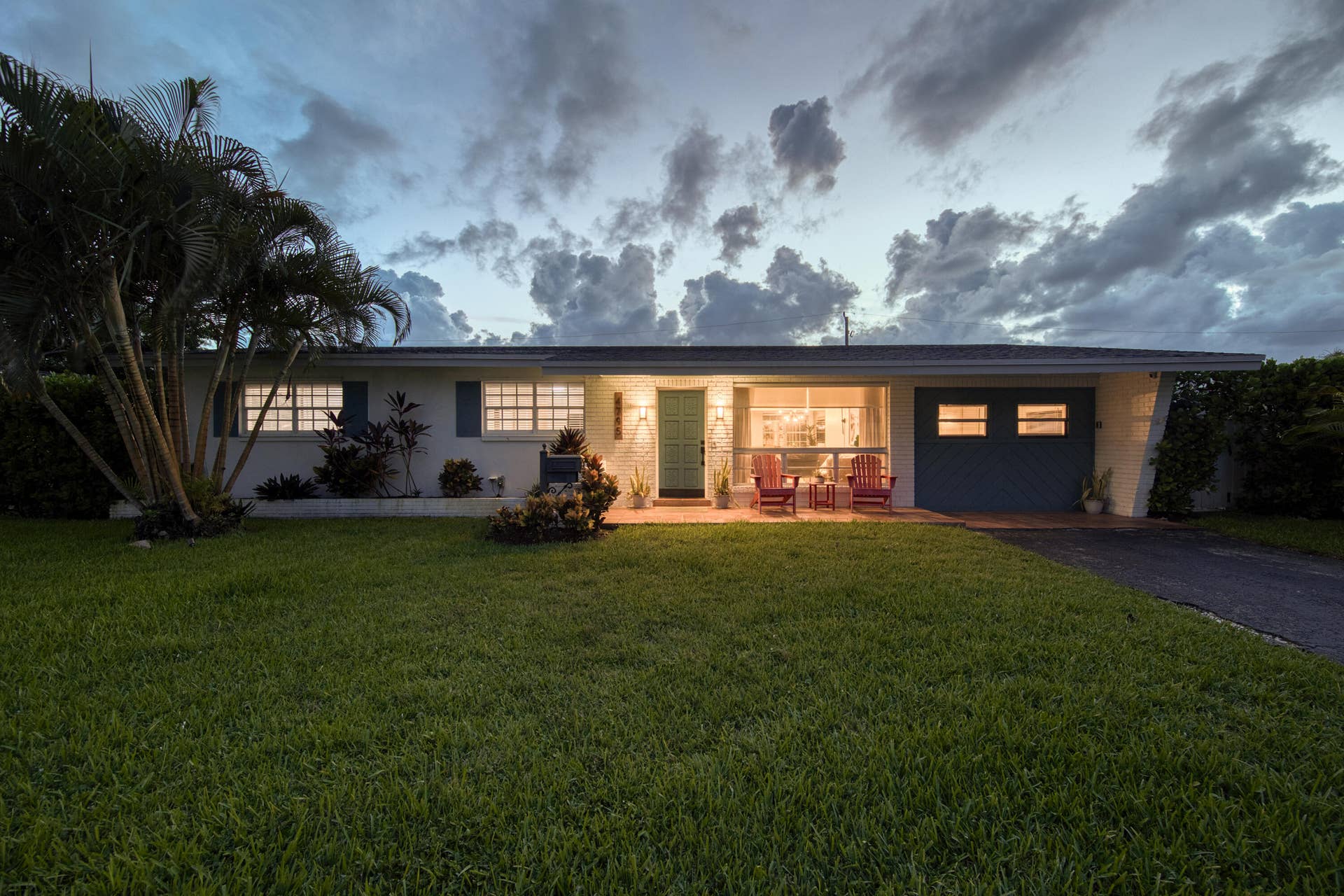 Modern single-story residence featuring a clean-lined facade with extensive glazing, illuminated interior spaces, and a recessed entry