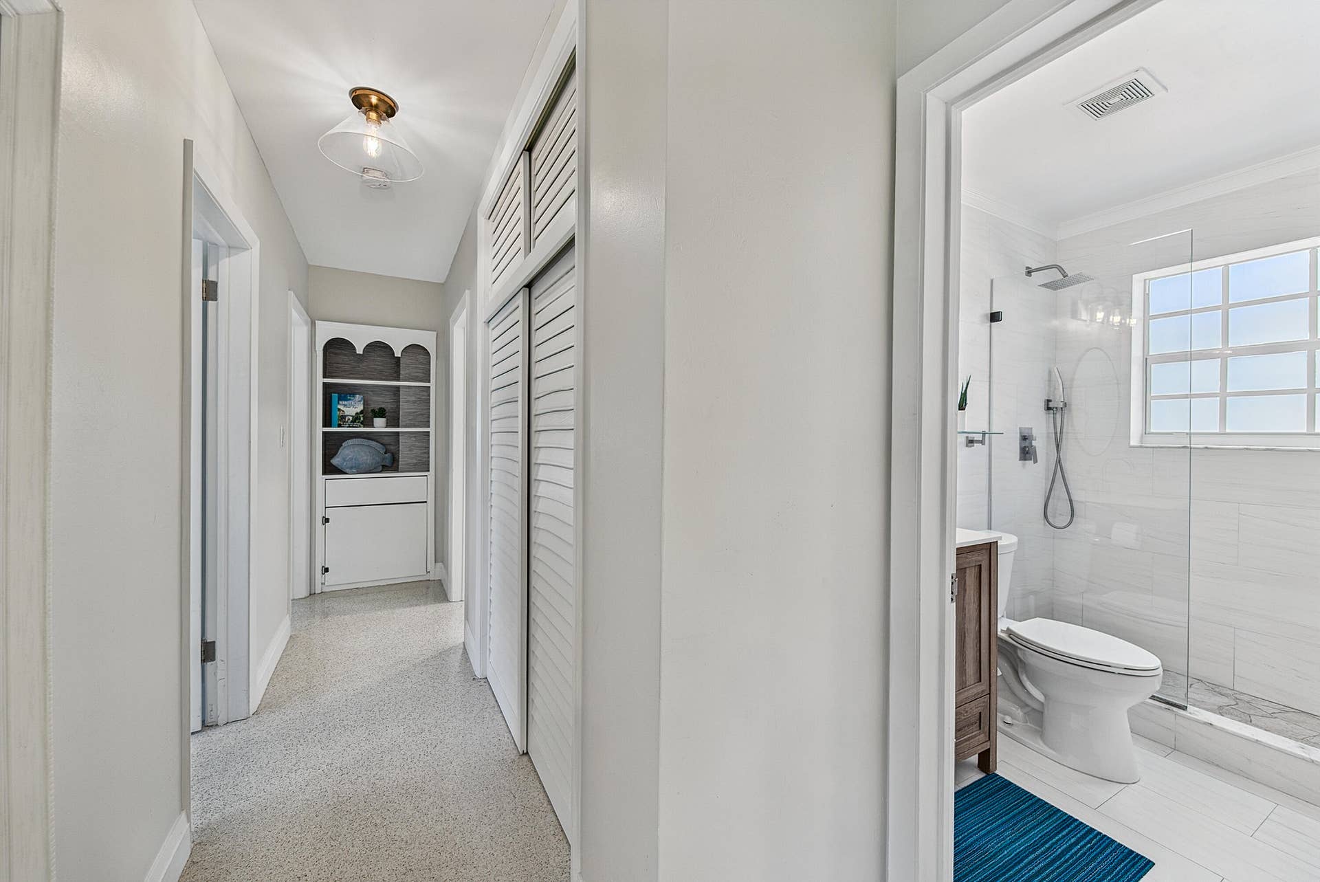 Hallway with built-in shelving, louvered closet doors, and recessed lighting