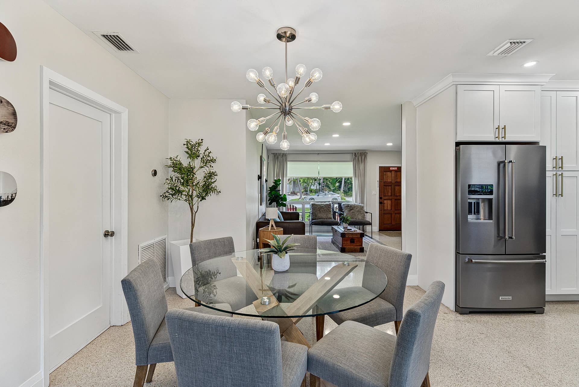 Open concept dining area with a contemporary sputnik chandelier, light-toned flooring, and white wall finishes