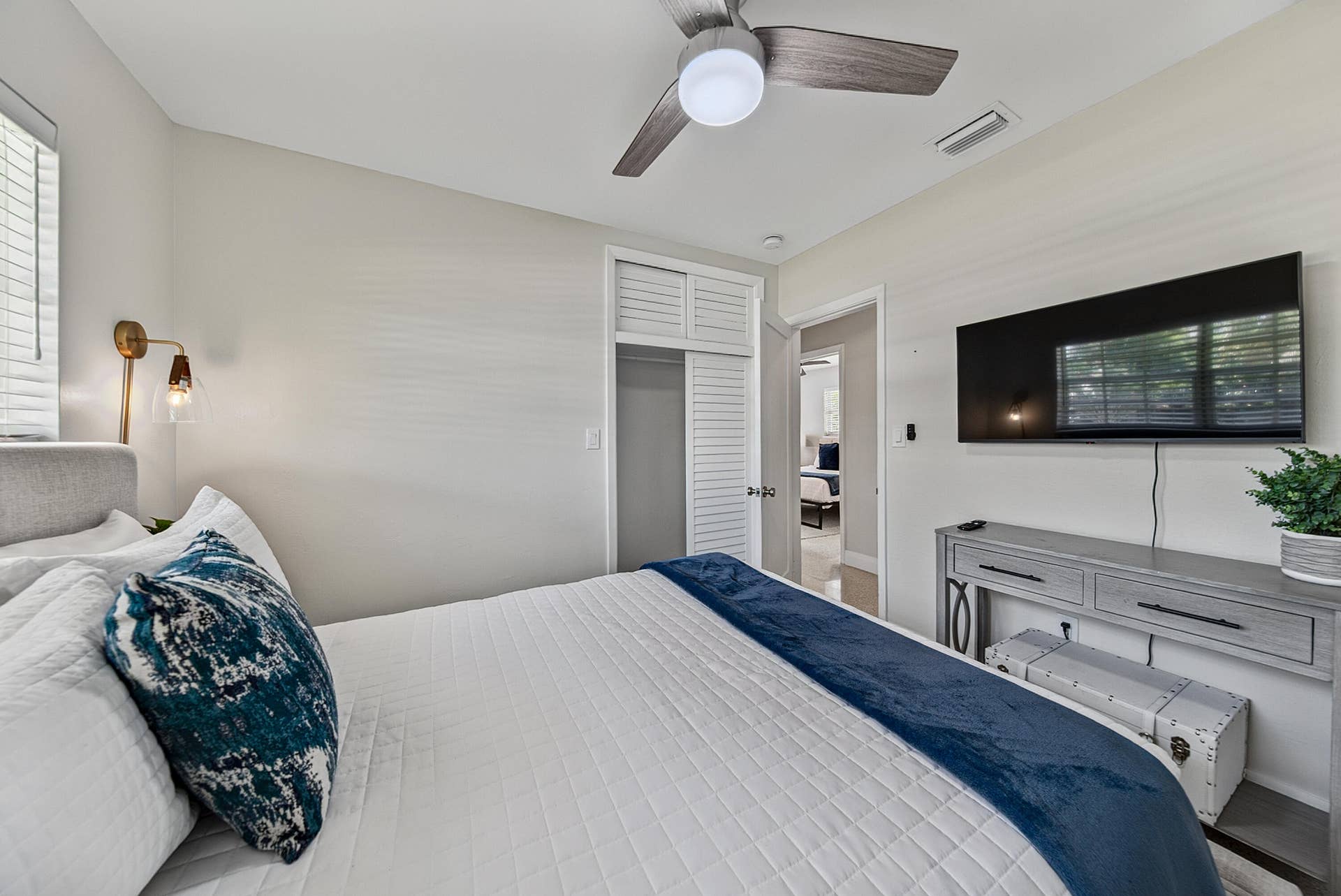 Integrated ceiling fan, louvered bi-fold closet doors, wall-mounted light fixture, window with blinds