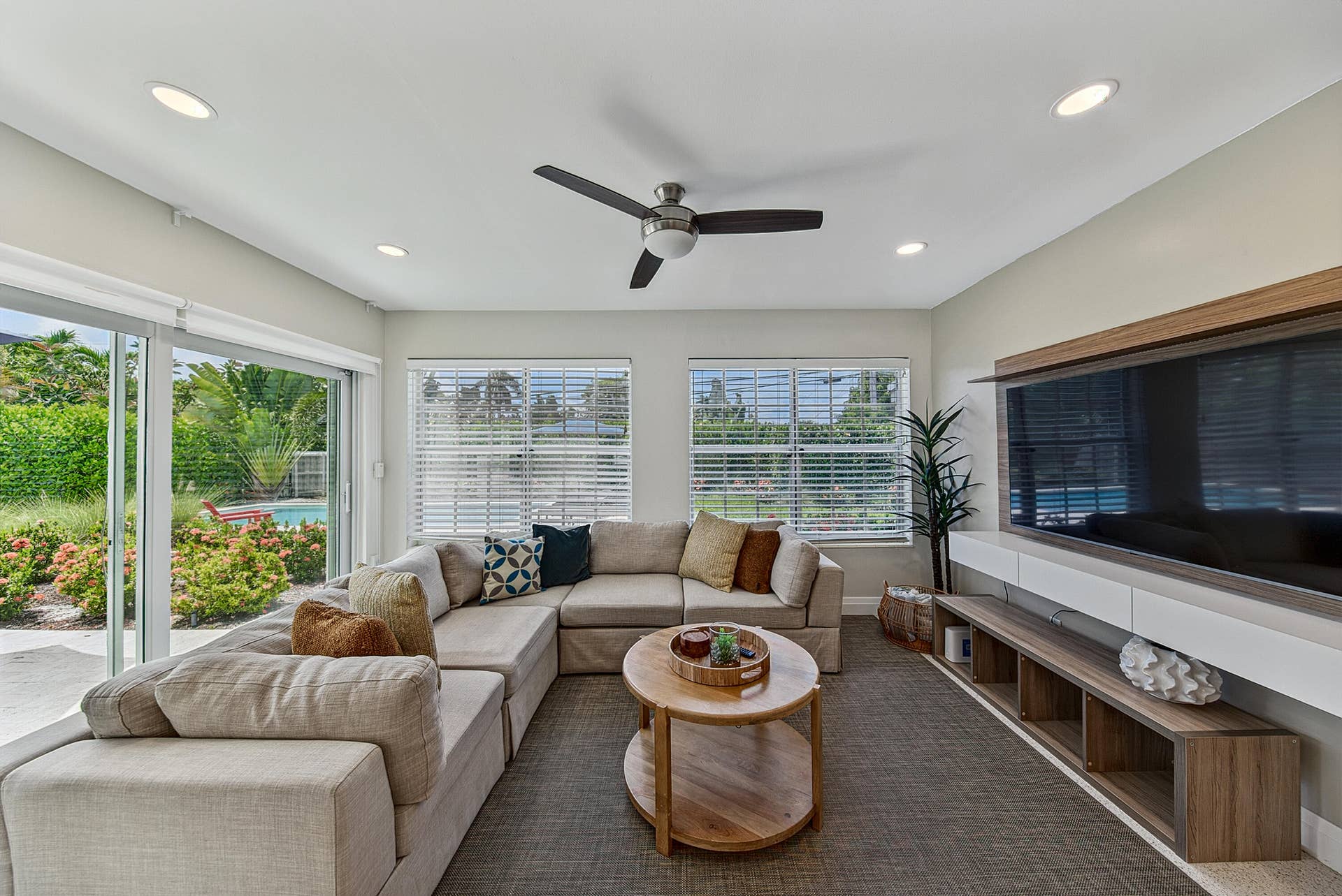 Recessed lighting, ceiling fan, impact sliding glass doors, multiple windows with blinds, and a built-in media console