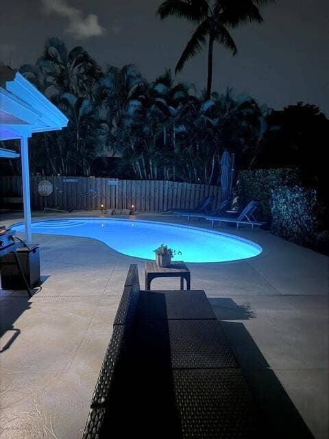 1201 SW 25TH Avenue, Boynton Beach, FL 33426 Relax and unwind beside the beautifully multicolored light, illuminating pool, creating a serene backyard after sunset. Comfortable outdoor seating set the perfect atmosphere for peaceful evenings and entertaining under the stars.