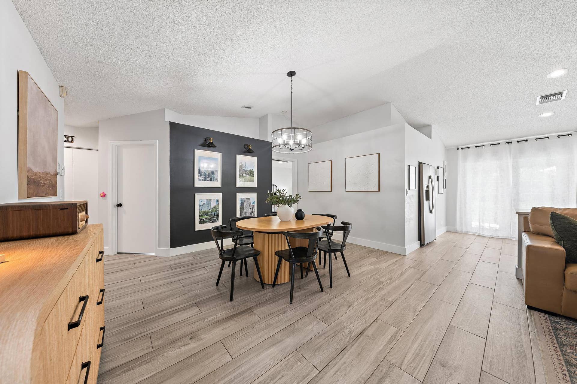 Open-concept living space with wood-finish flooring, a contemporary chandelier, recessed lighting, and a stainless steel refrigerator