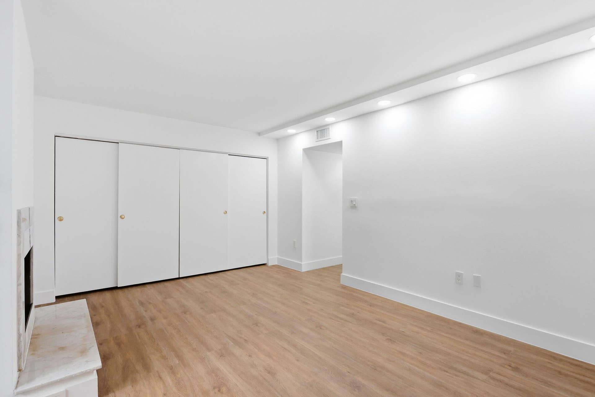 1222 Hillsboro Mile, #15, Hillsboro Beach, FL 33062 Recessed lighting, wood-finish flooring, white walls, built-in closet with sliding doors, and a fireplace with a stone surround