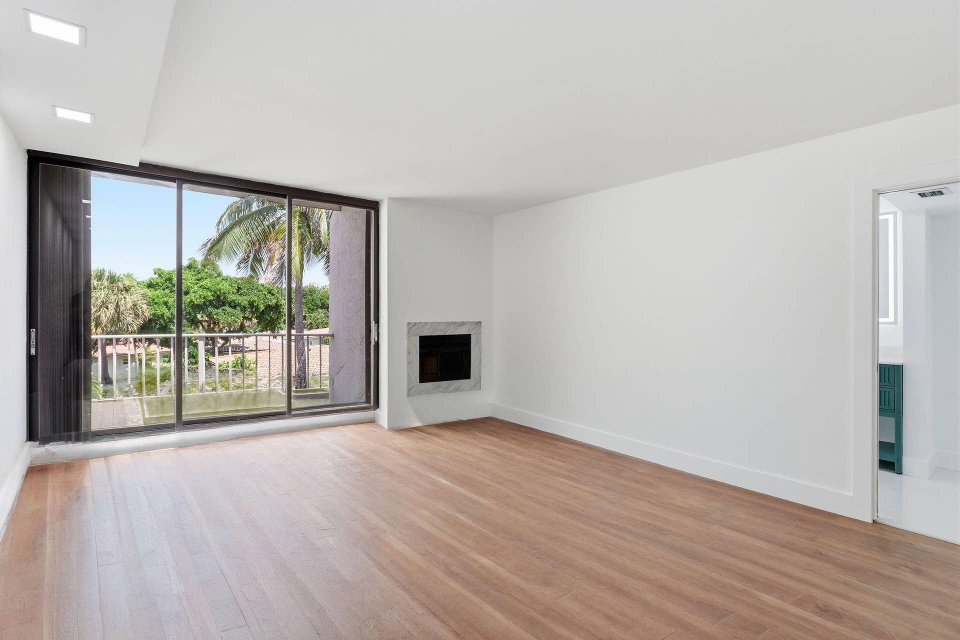 1222 Hillsboro Mile, #15, Hillsboro Beach, FL 33062 Wood-finish flooring throughout, recessed ceiling lighting, a built-in fireplace with a stone surround, and an expansive sliding glass door to the exterior balcony