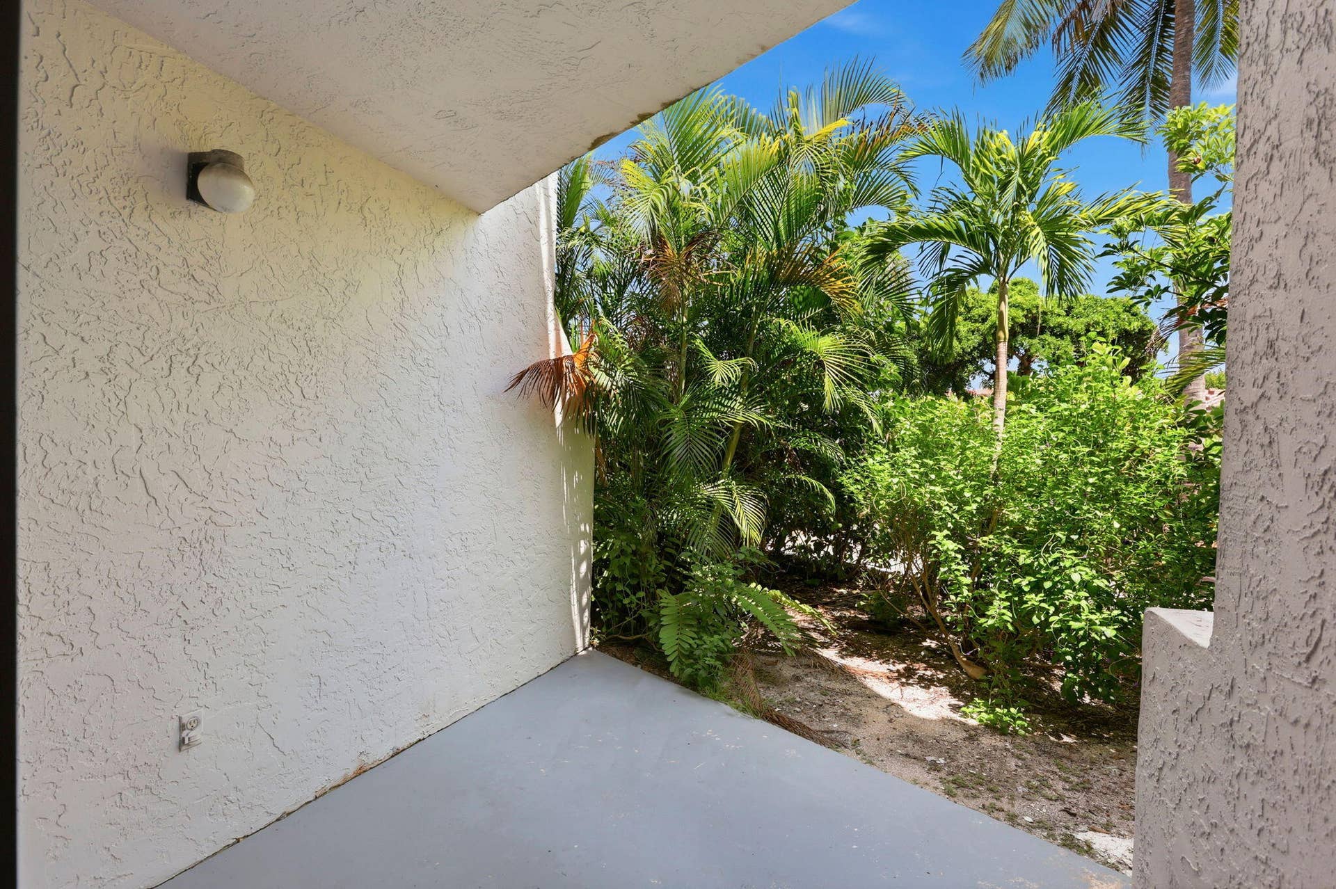 1222 Hillsboro Mile, #15, Hillsboro Beach, FL 33062 Outdoor patio featuring textured stucco walls and tropical landscaping