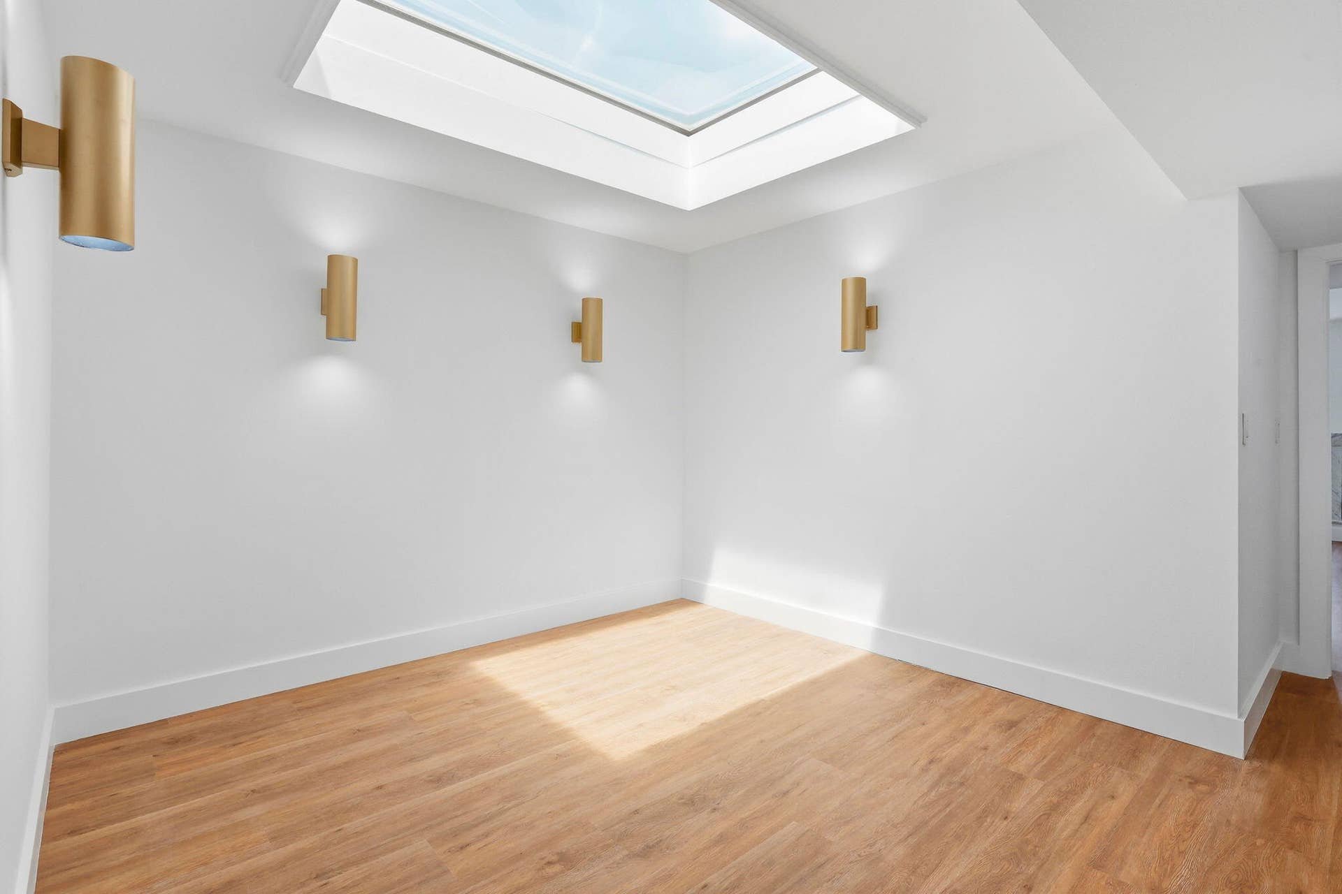 1222 Hillsboro Mile, #15, Hillsboro Beach, FL 33062 Skylight with natural light, wood-finish flooring, white walls, and three gold-tone wall sconces