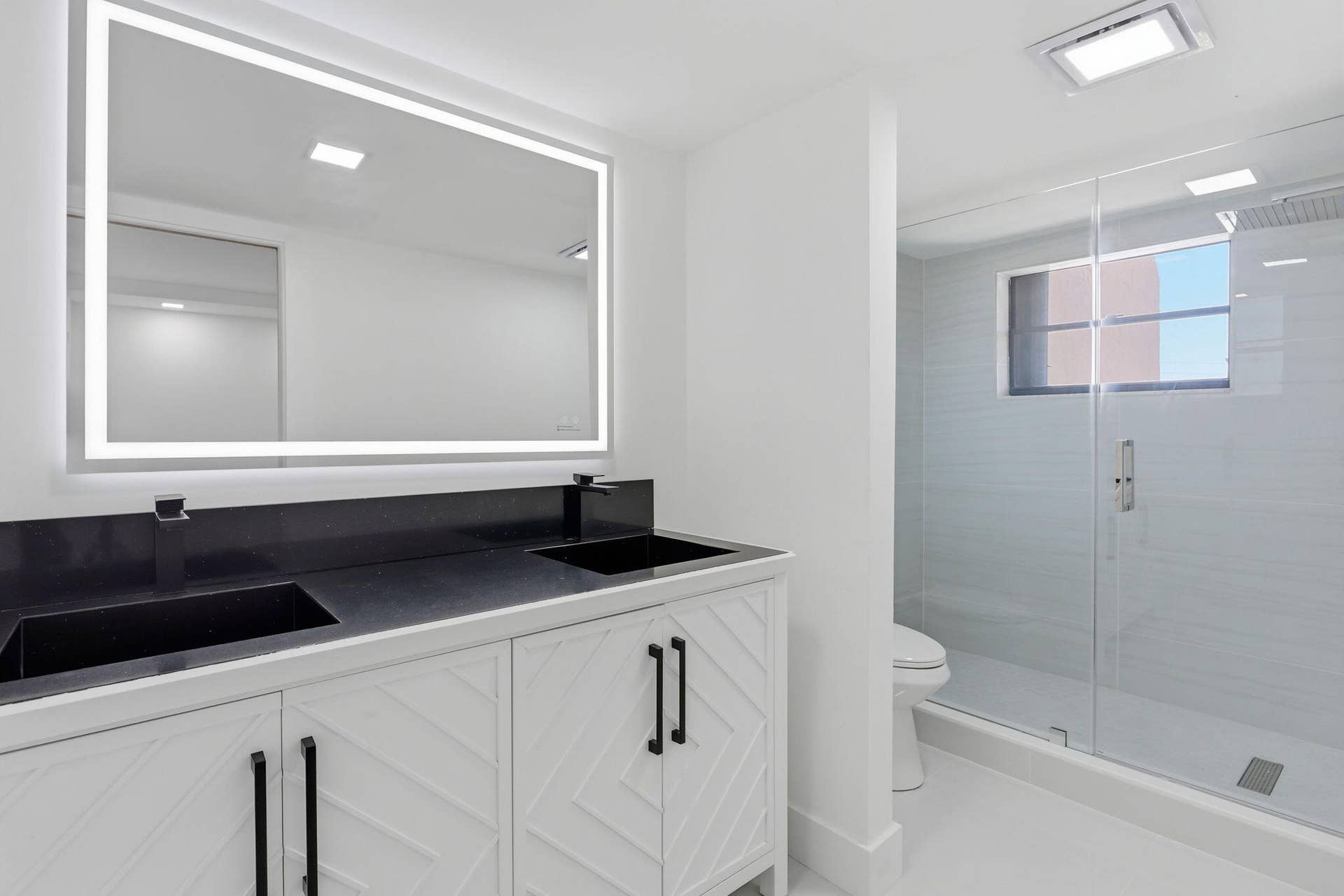 1222 Hillsboro Mile, #15, Hillsboro Beach, FL 33062 Dual vanity with integrated sinks, black countertop, and white cabinetry